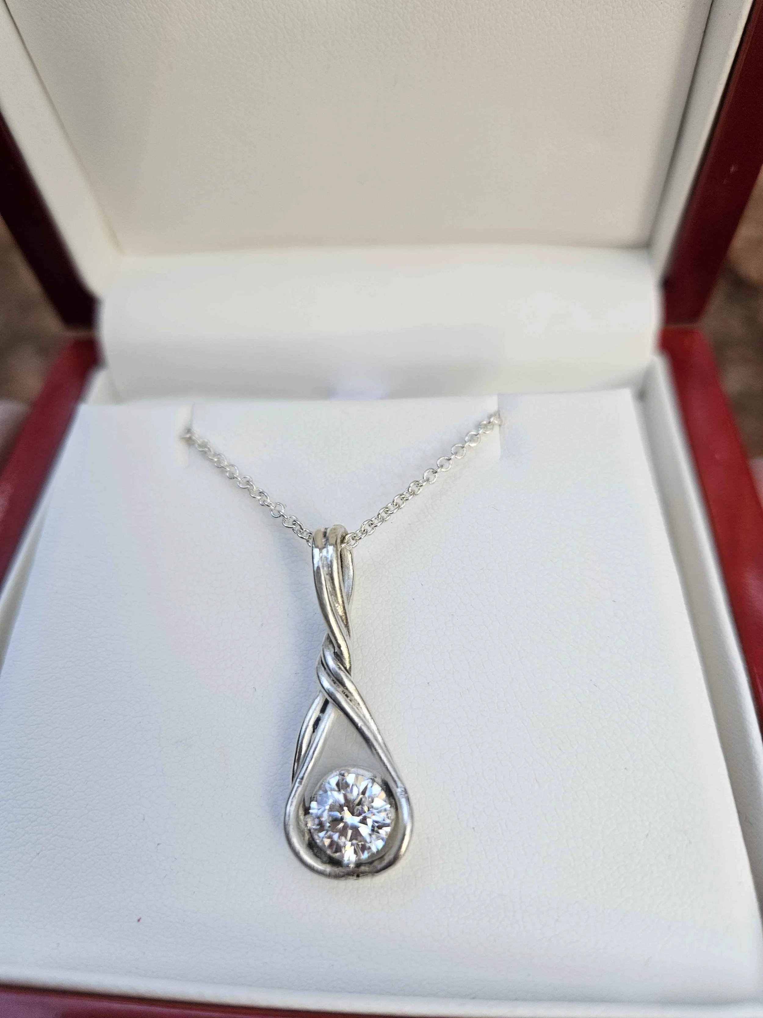 Silver necklace with a large round gemstone pendant in a jewelry box.