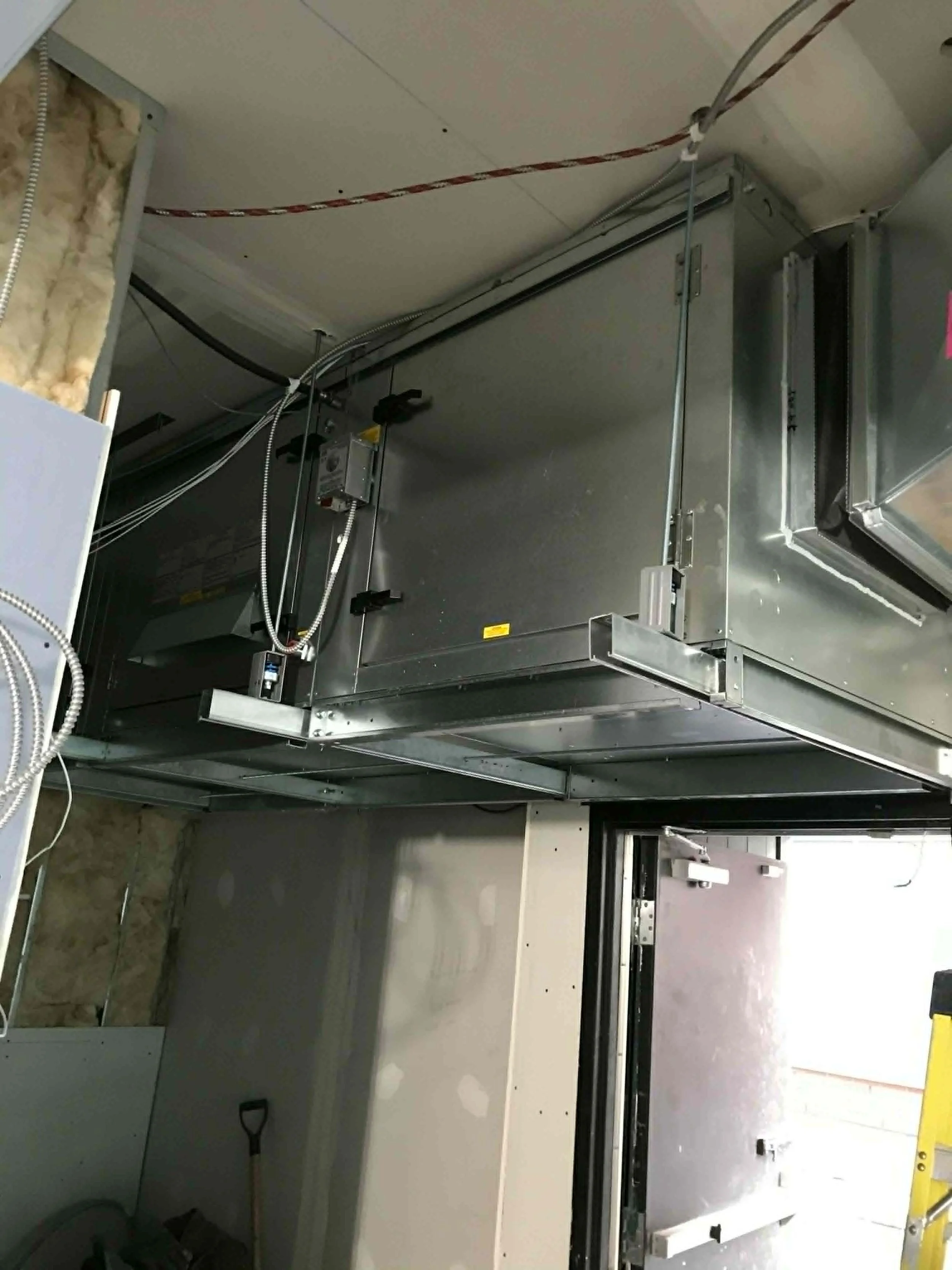 Photo d'une zone de construction ou d'installation électrique montrant des câbles, des conduits et des boîtes de câblage en cours de montage.