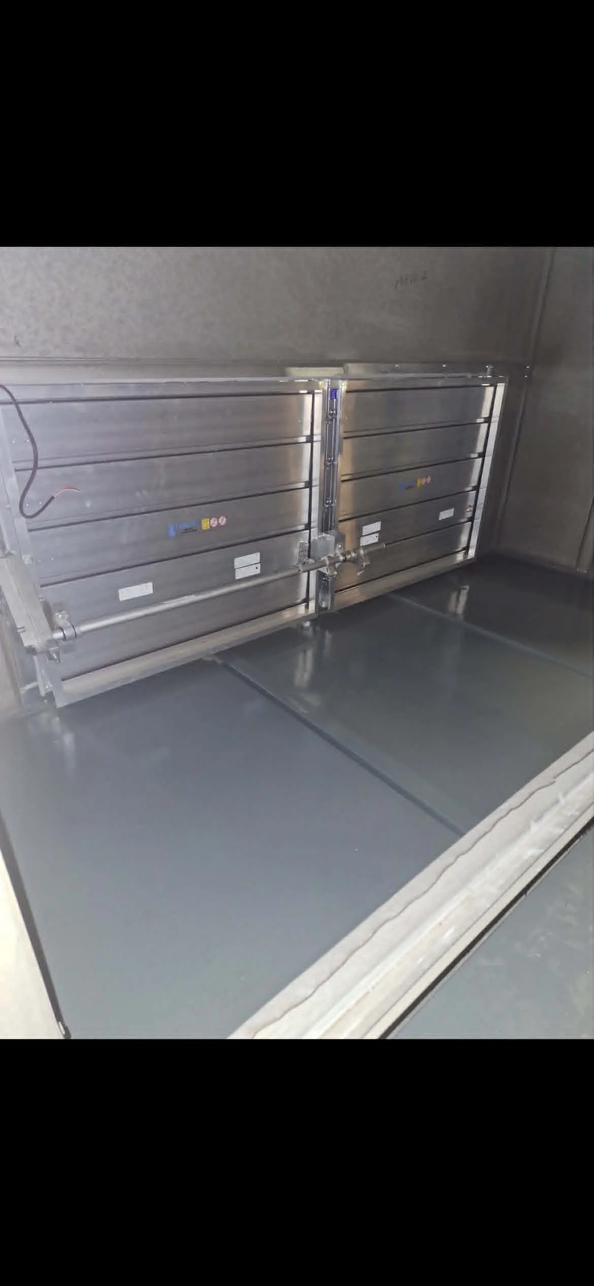 Une porte de cage d'ascenseur en acier inoxydable fermée, avec une serrure au centre.