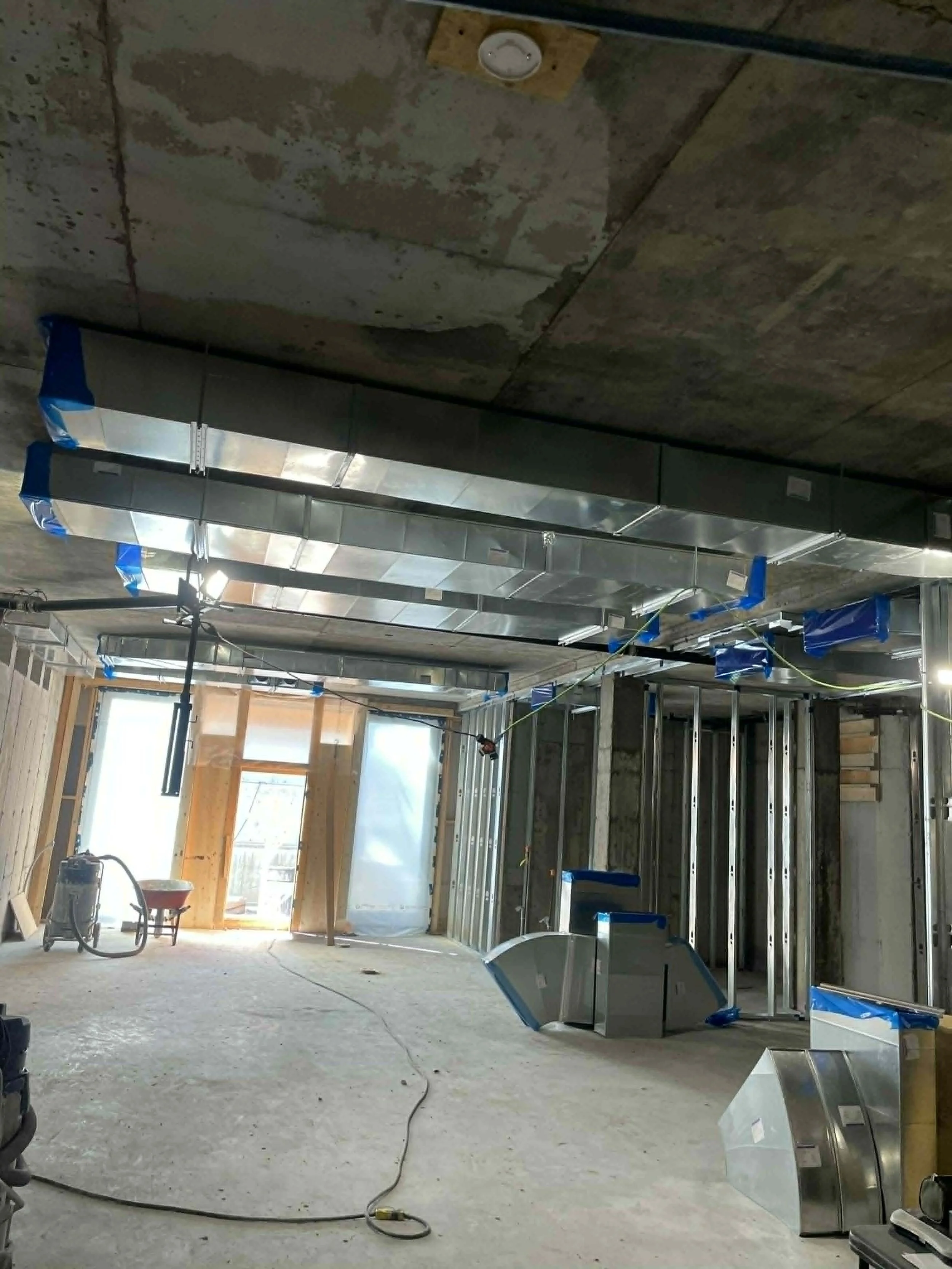 Intérieur d'un bâtiment en construction avec des structures métalliques et des câbles suspendus.