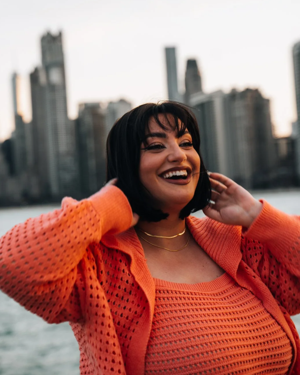 A woman smiling and smiling in front of a city skyline.