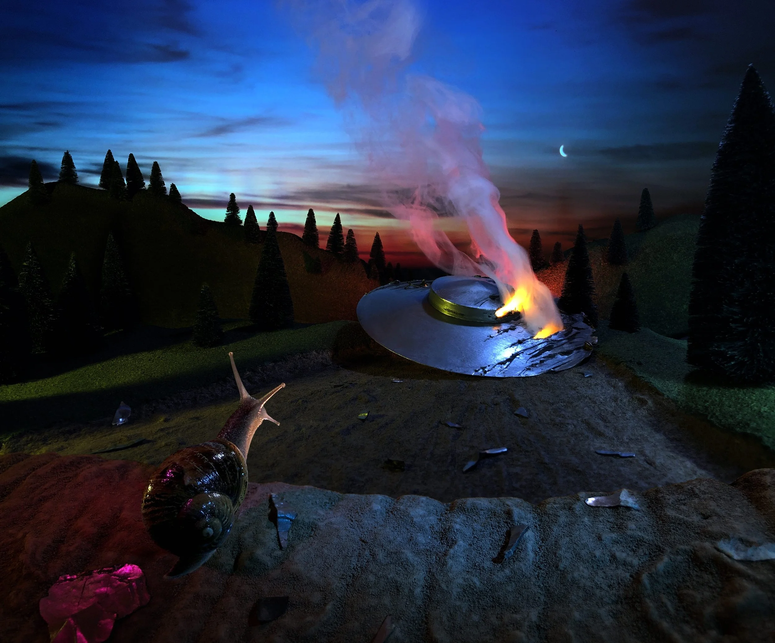 A nighttime scene with colorful sky, distant crescent moon, smoke rising from a crashed UFO, and a snail in the foreground on the ground. Something is afoot in Slimetown...