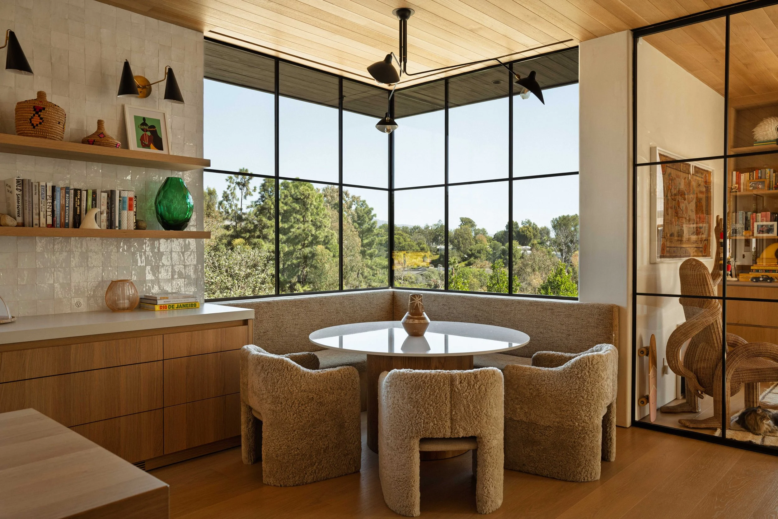 Breakfast nook with round table and bouclé chairs in a corner of windows, Point Dume Malibu