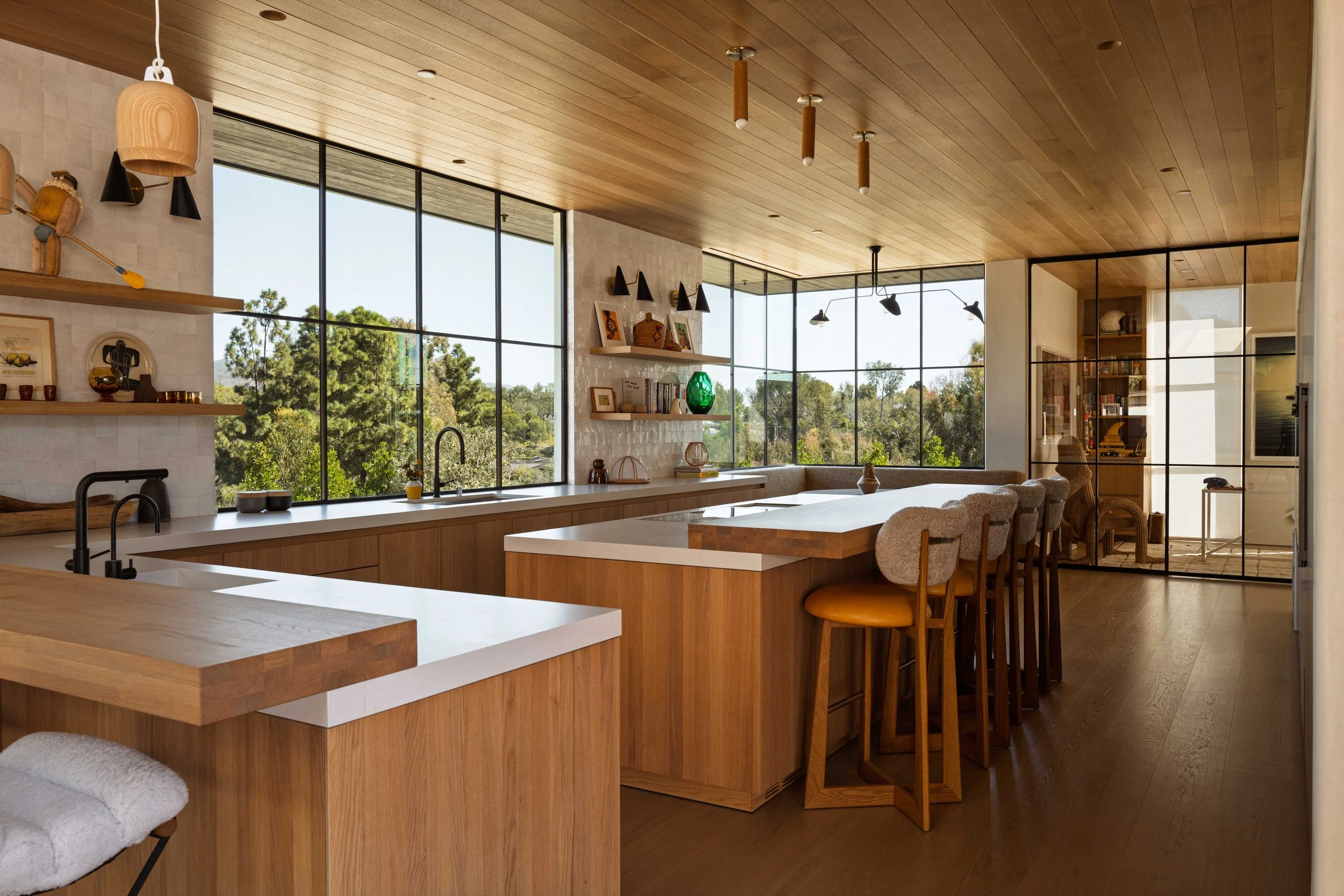 Wood kitchen with island, bar stools, and steel-framed windows, Malibu home interior photography