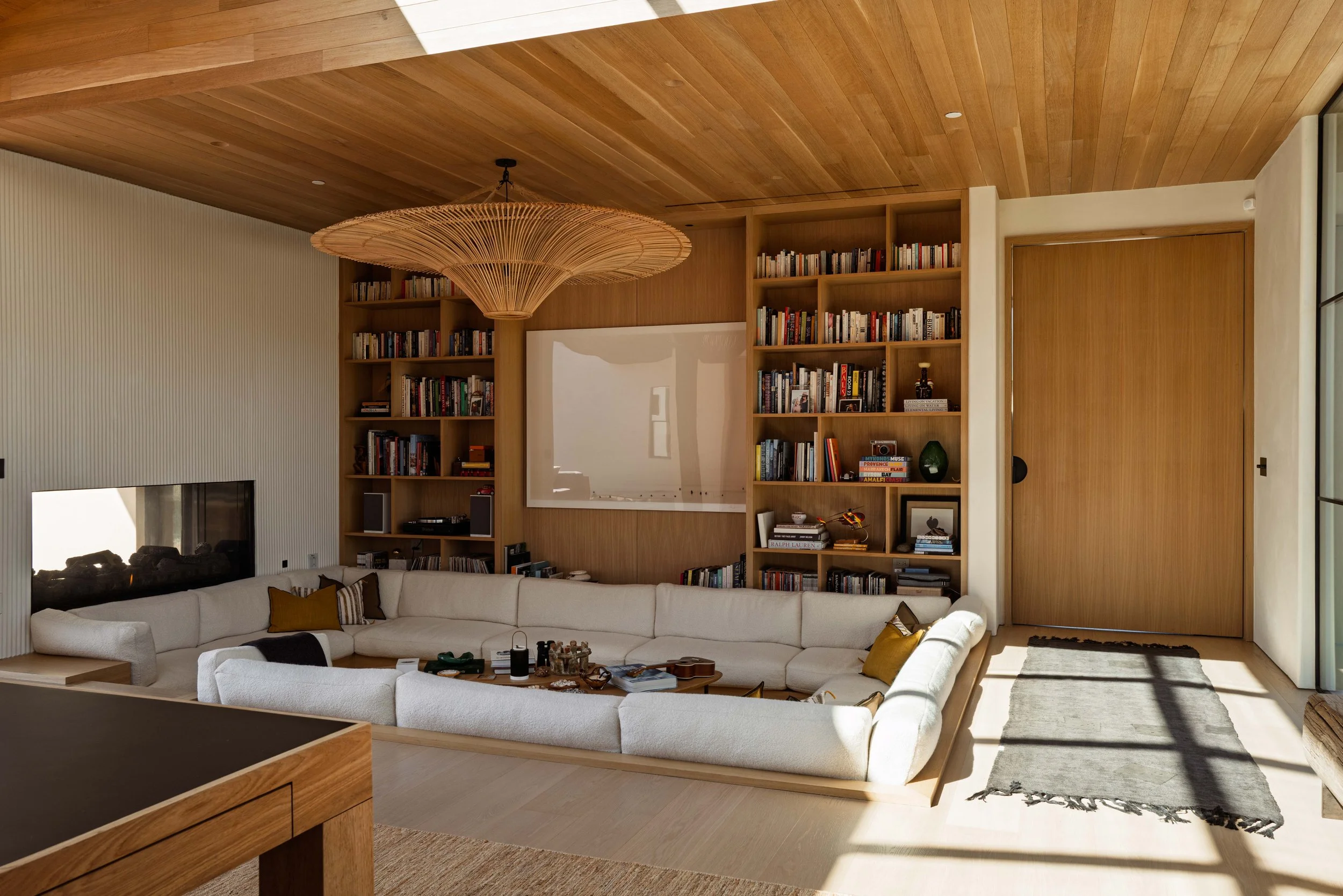 Sunken white sectional with built-in bookshelves and woven pendant, Point Dume living room by Peggy North