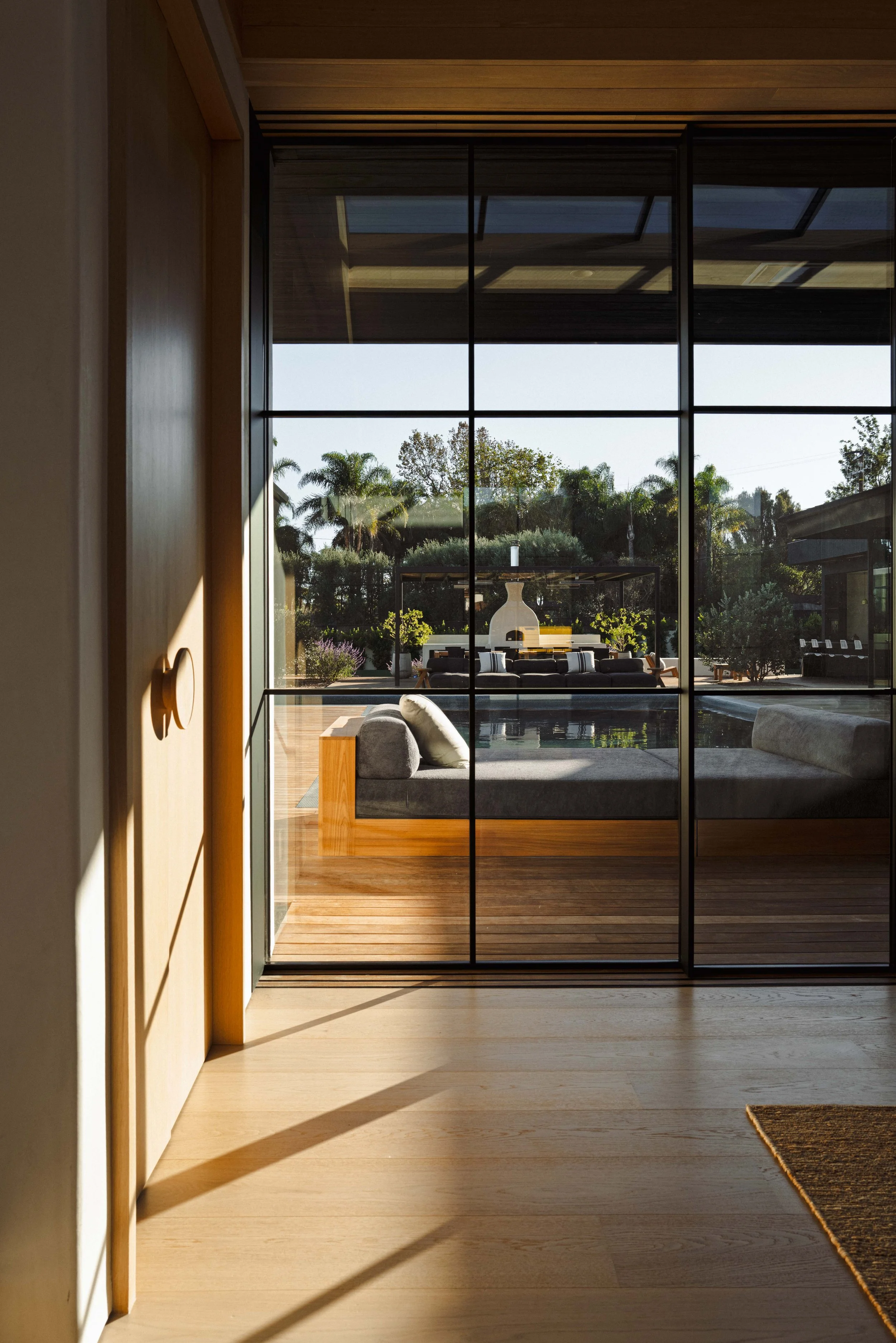 Steel-framed glass doors opening onto a sunken outdoor lounge, Malibu architecture photography