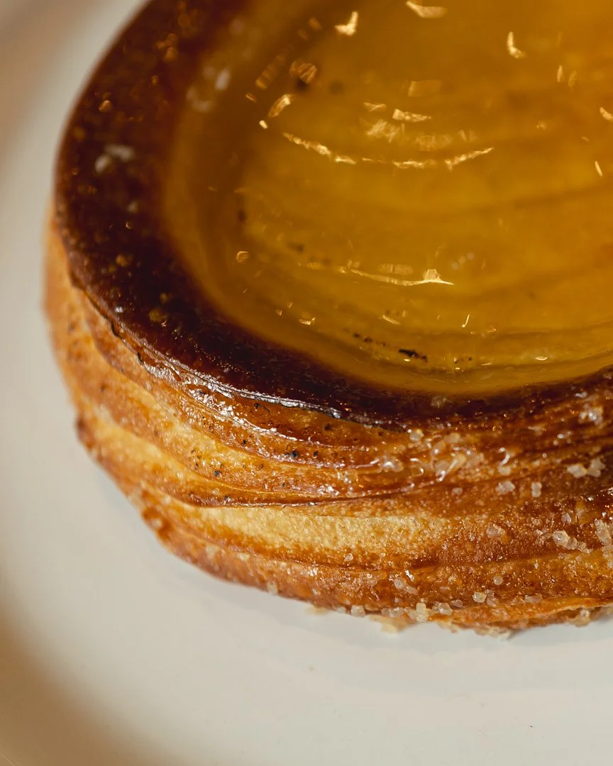 Close-up of a glazed apple tart’s flaky edge, food photography by Anne Demay