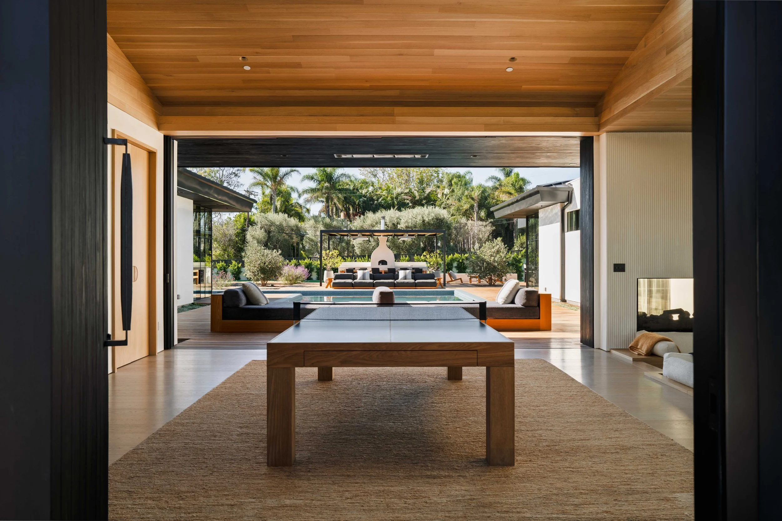 Wooden ping-pong table on a jute rug with views to the pool terrace, Malibu interior photography