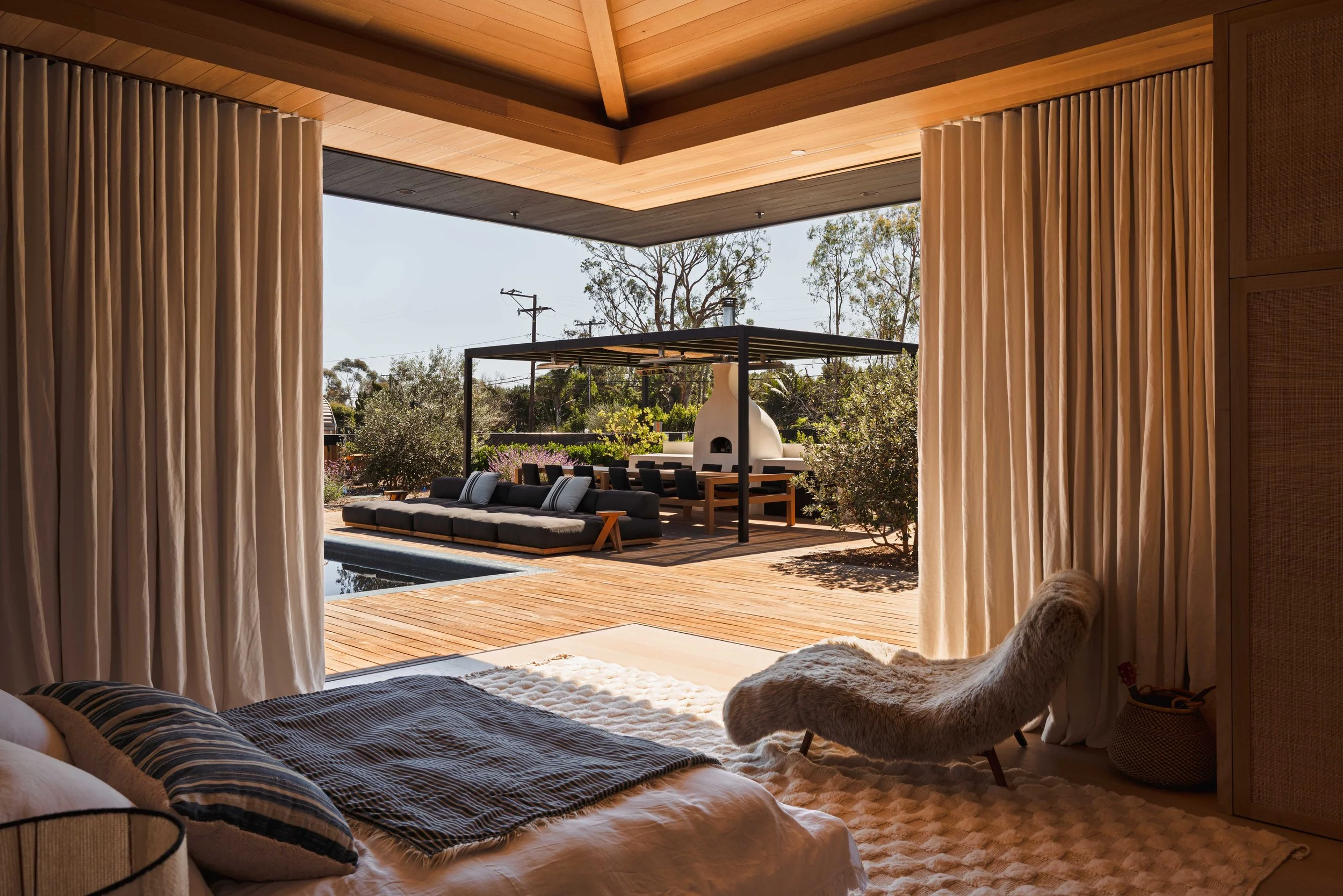 Primary bedroom opening onto the pool deck and pergola, Malibu interior photography