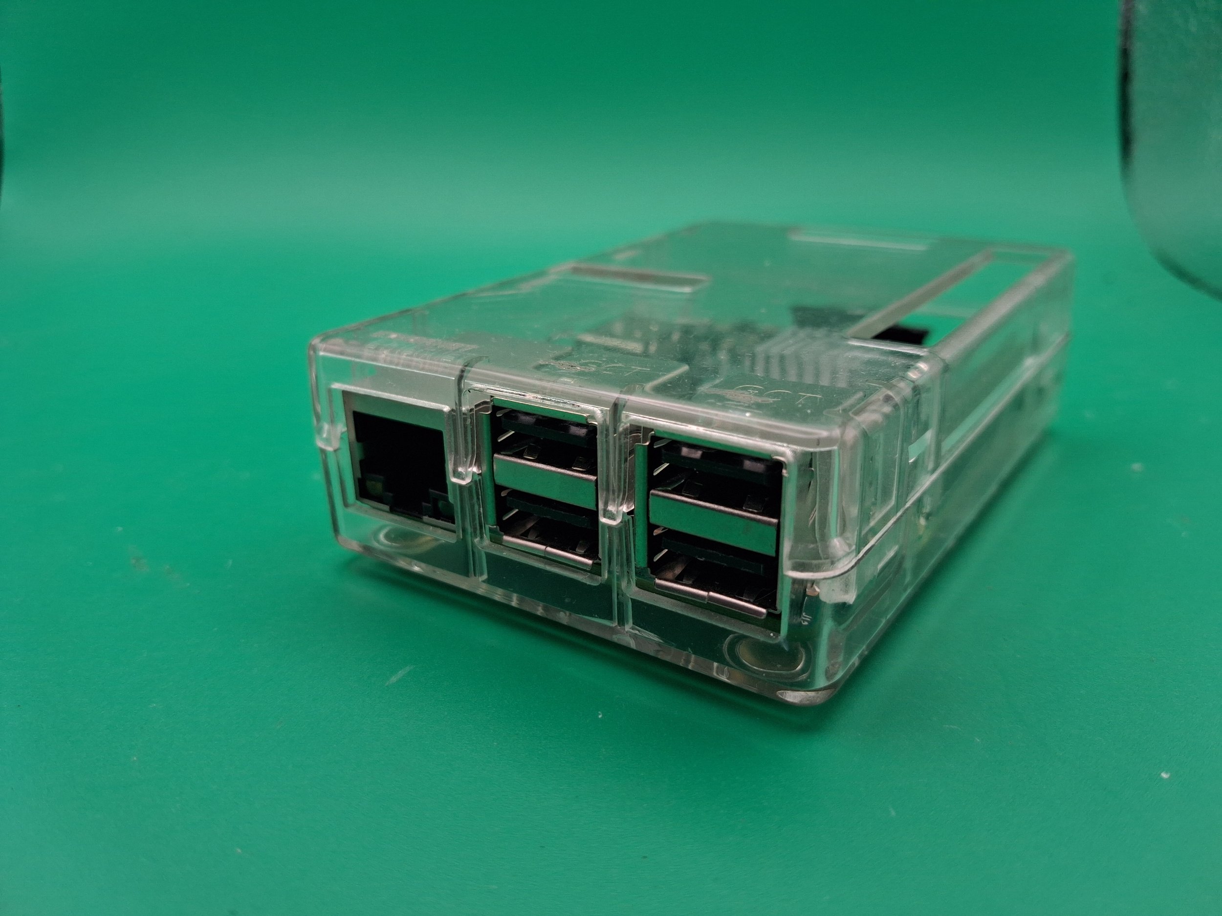 A clear plastic multi-port Ethernet splitter on a green background.