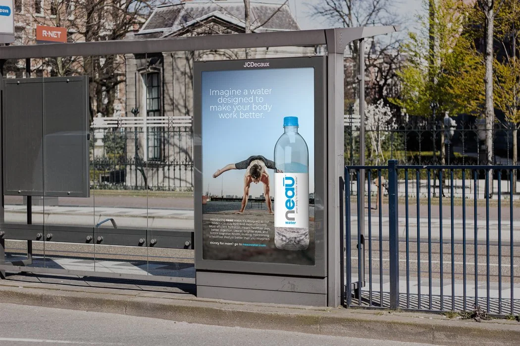 An outdoor bus stop with an advertisement for water featuring a woman doing yoga and a large water bottle with the brand name 'neau' and text promoting hydration.