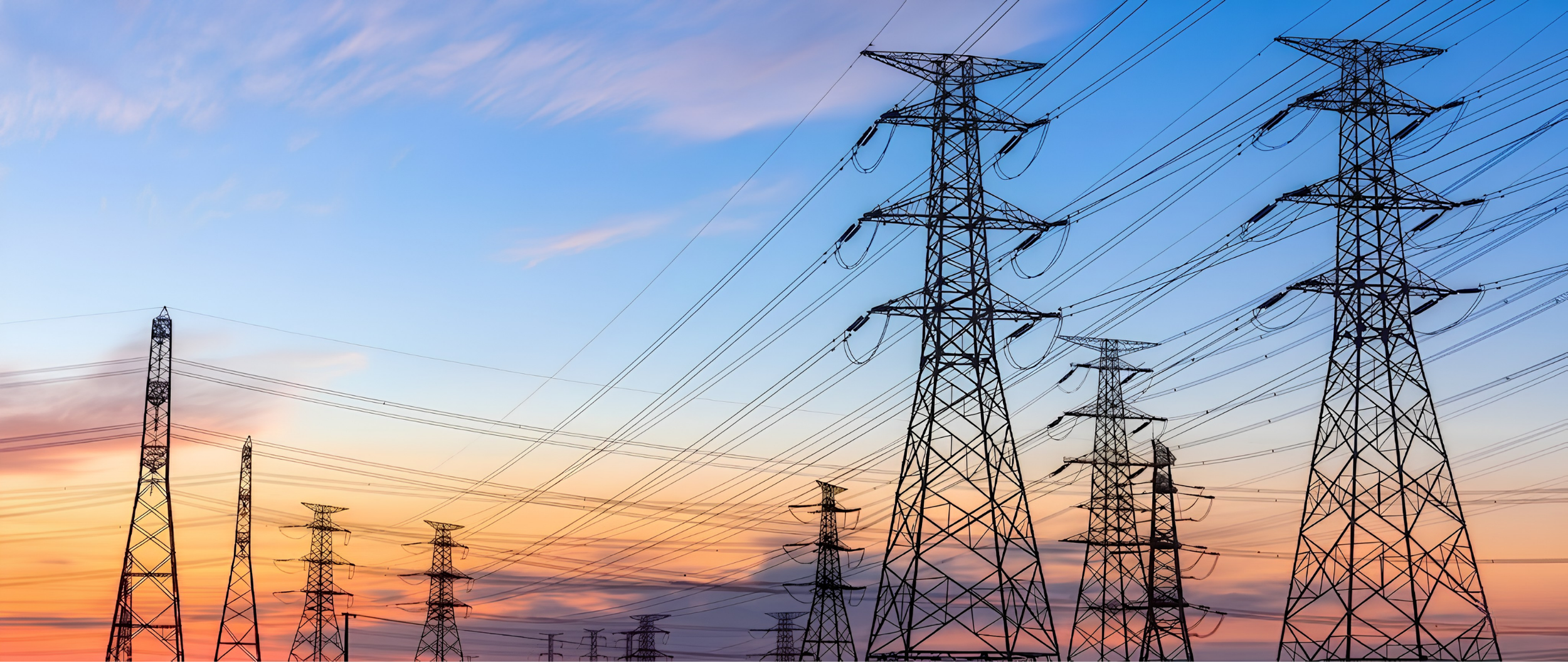 Multiple electric transmission towers against a colorful sunset sky.