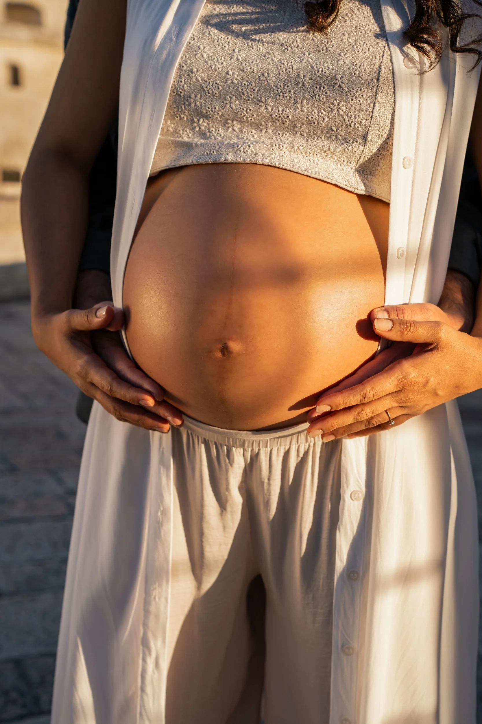 Elegant fine-art maternity details highlighting a beautiful baby bump against the rustic, historic architecture of Puglia.