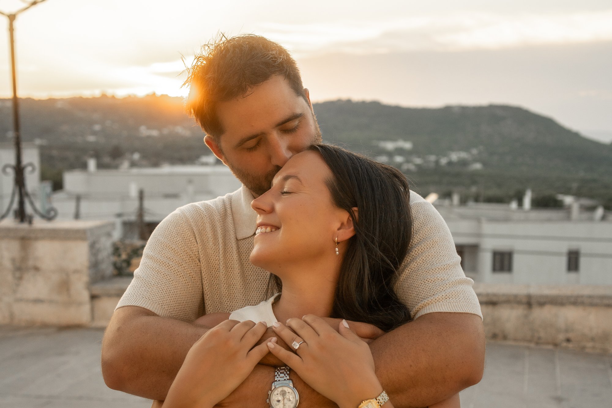 Romantic engagement and proposal photoshoot in Ostuni - Puglia, Italy showing a happy couple embracing at golden hour sunset.