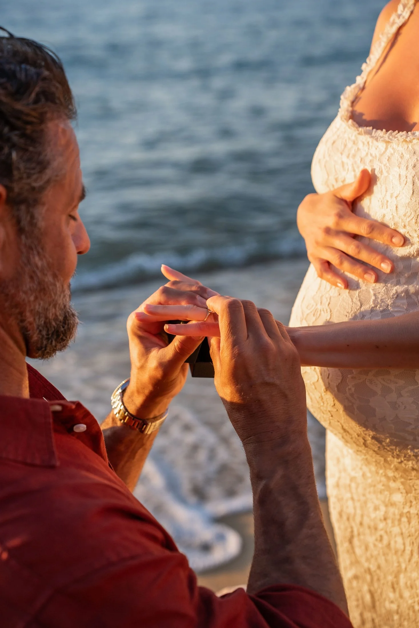 Groom-to-be placing an engagement ring on his fiance's finger during a sunset proposal in Puglia.
