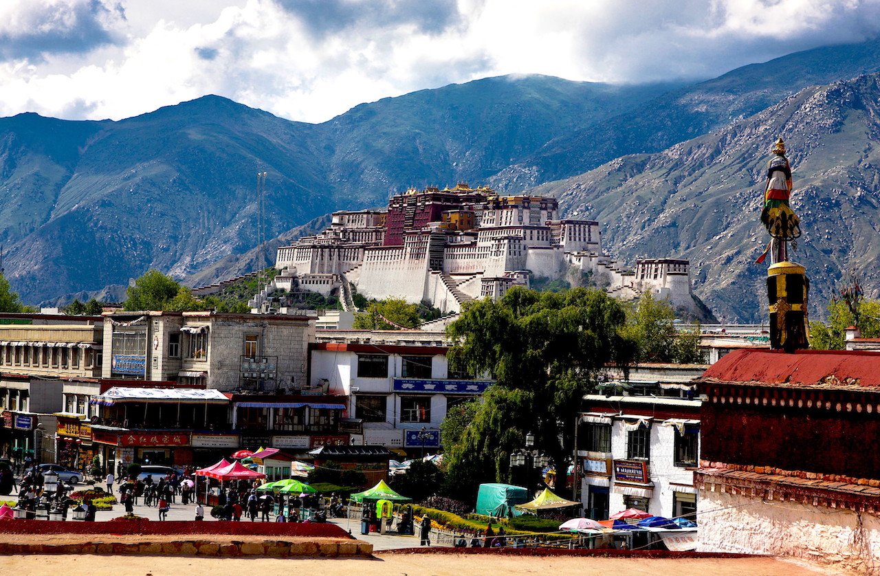 Vista de un fuerte en una ciudad, con un mercado y montañas al fondo.