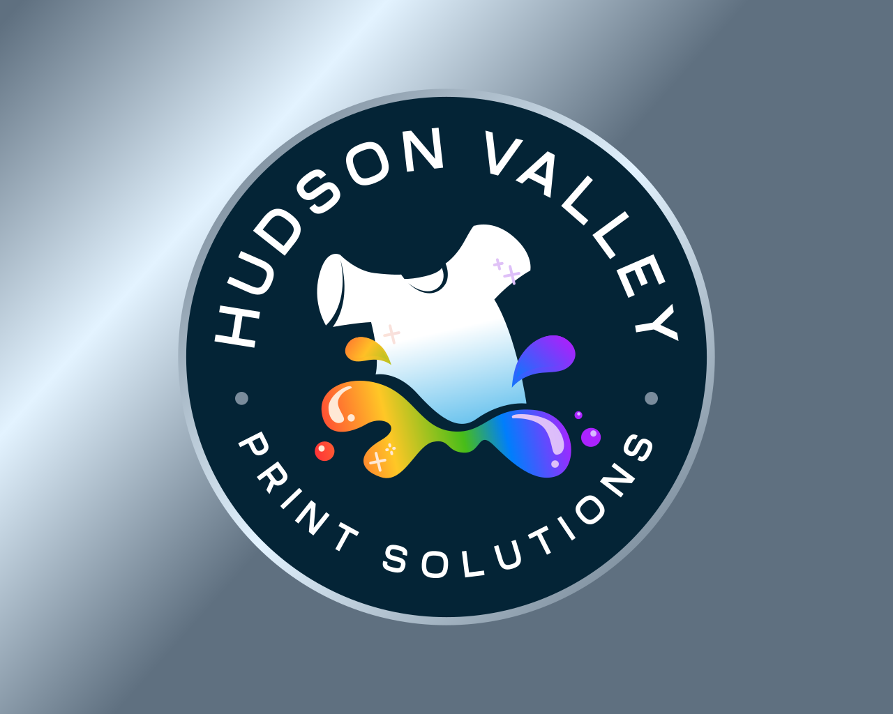 A circular logo with the text 'HUDSON VALLEY PRINT SOLUTIONS' around the top edge. The center features a T-shirt with rainbow-colored ink splashing out from it.