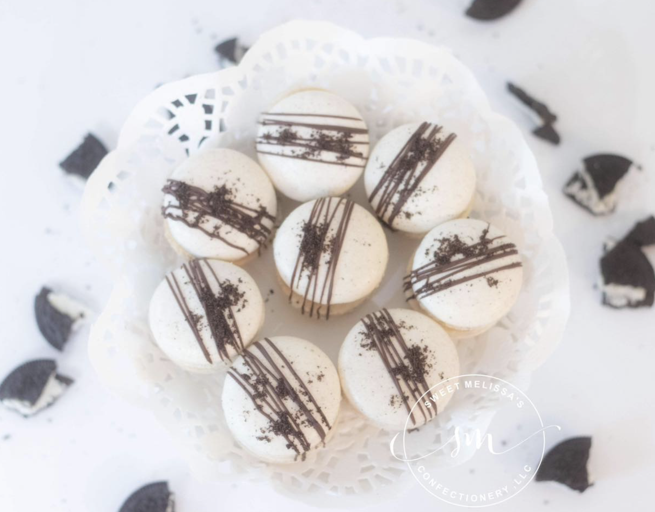 White chocolate truffles decorated with dark chocolate drizzle and cocoa powder on a white doily.