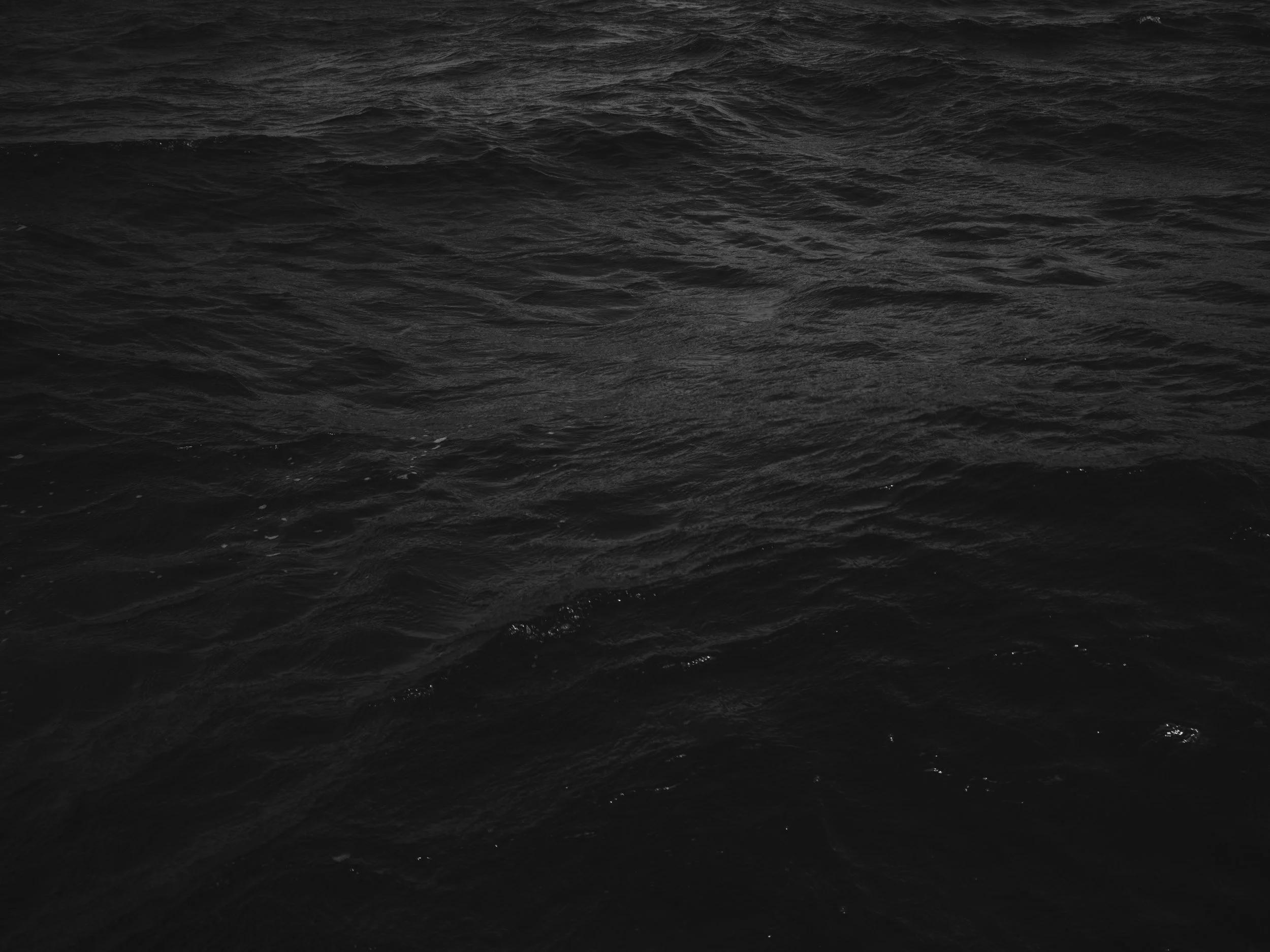 Dark, choppy ocean water with small waves and ripples.