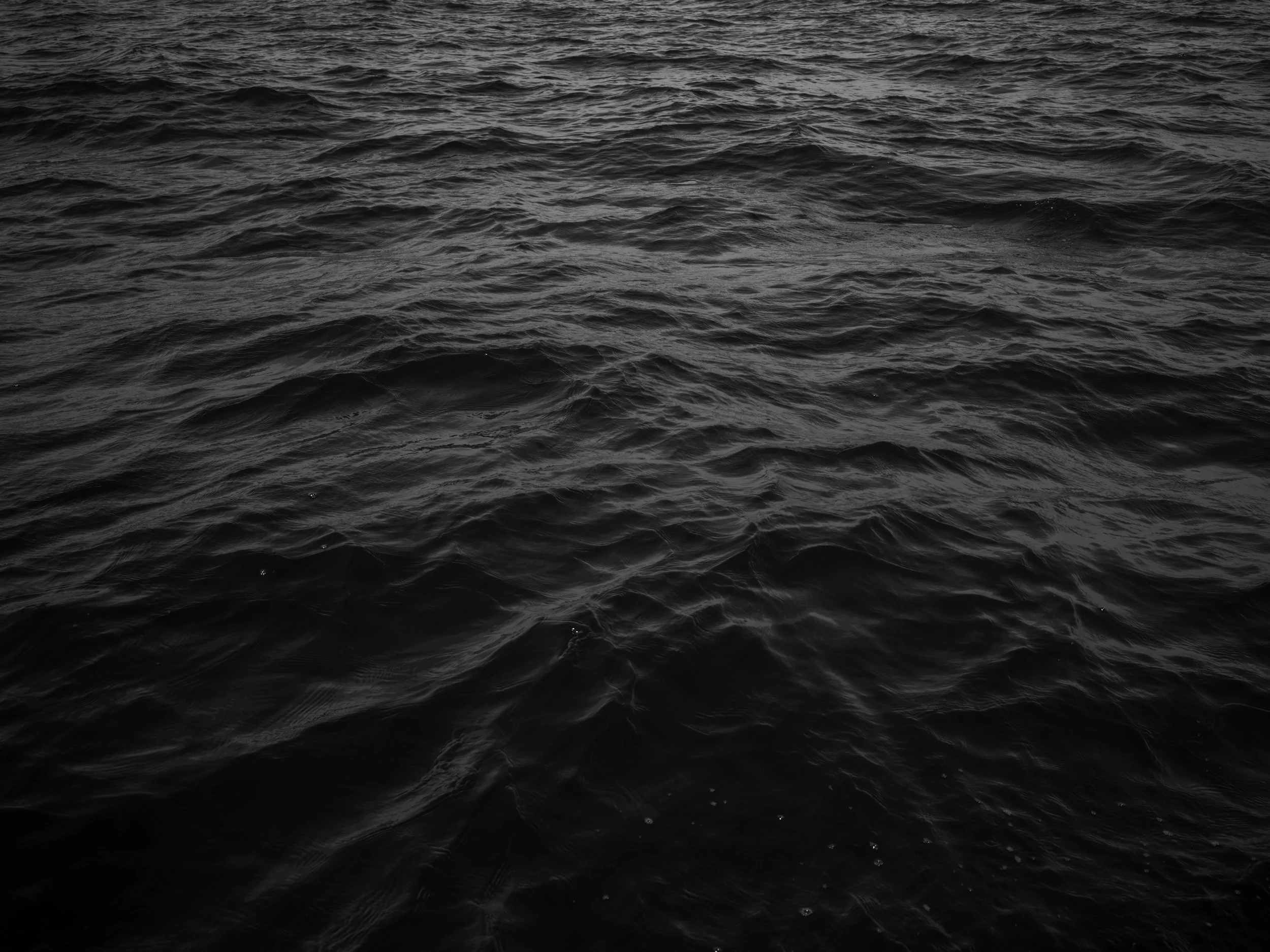 Black and white photograph of ocean waves with ripples and textures.