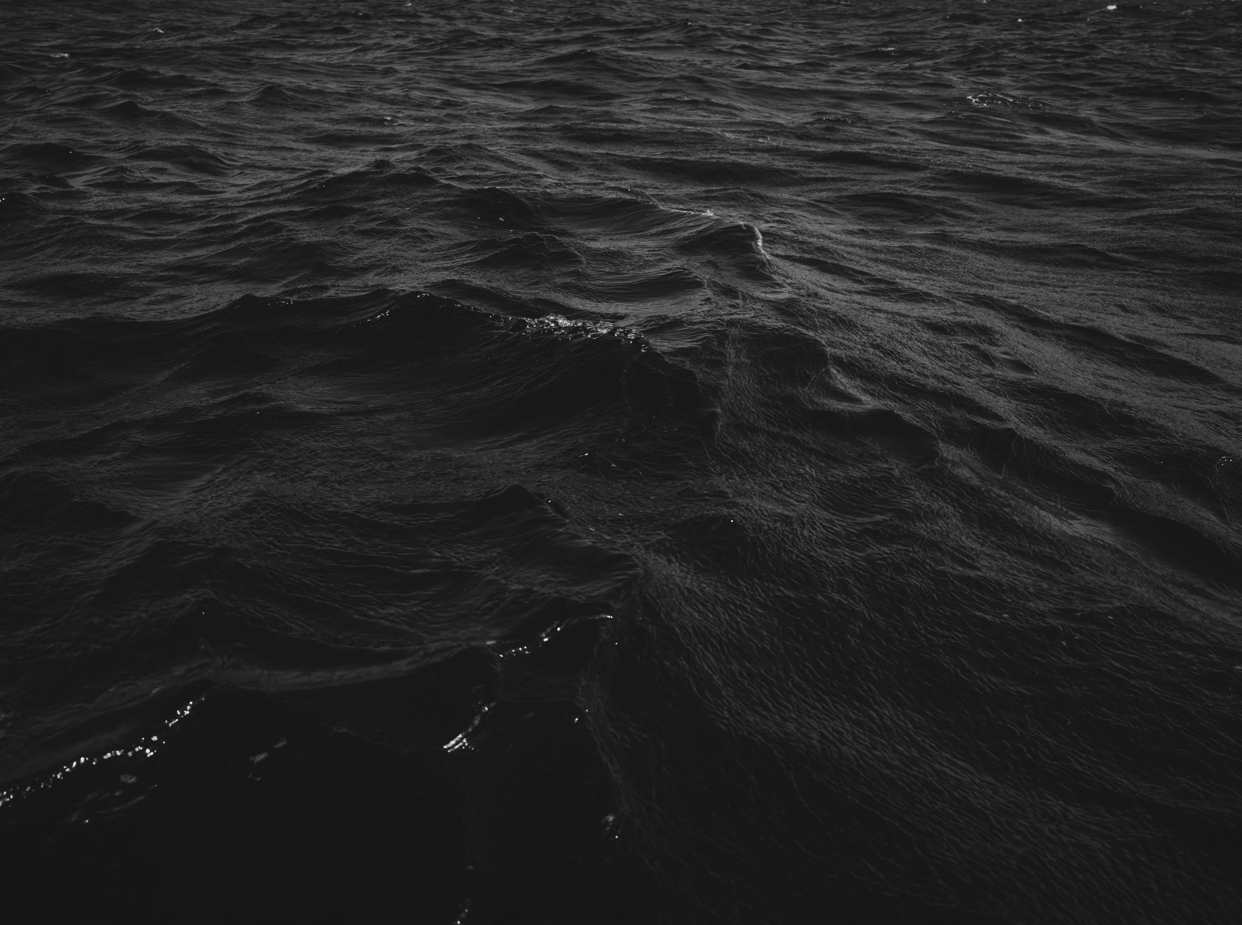 Dark, choppy ocean water with waves and reflections.