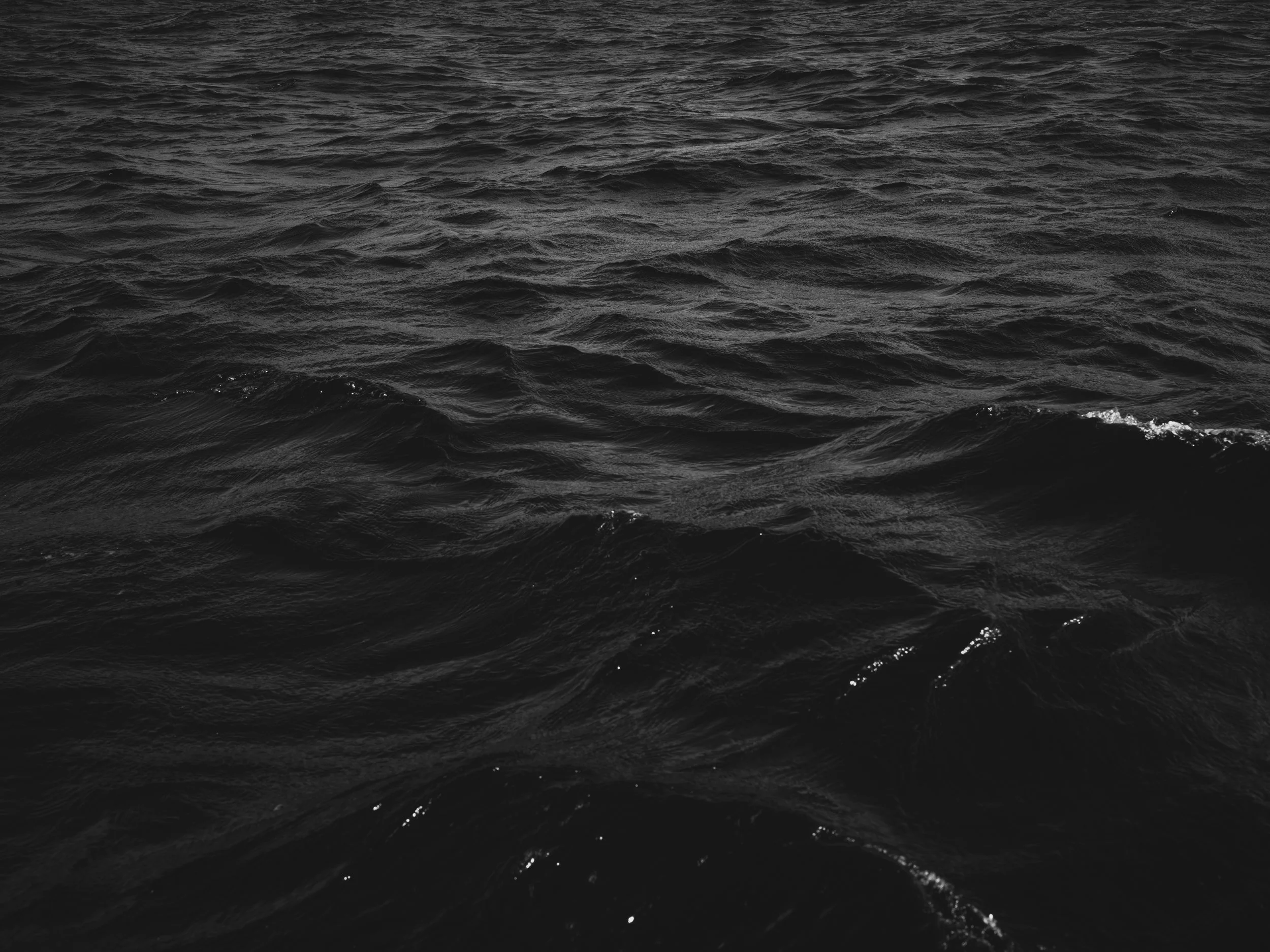 Black and white photo of the ocean with waves.