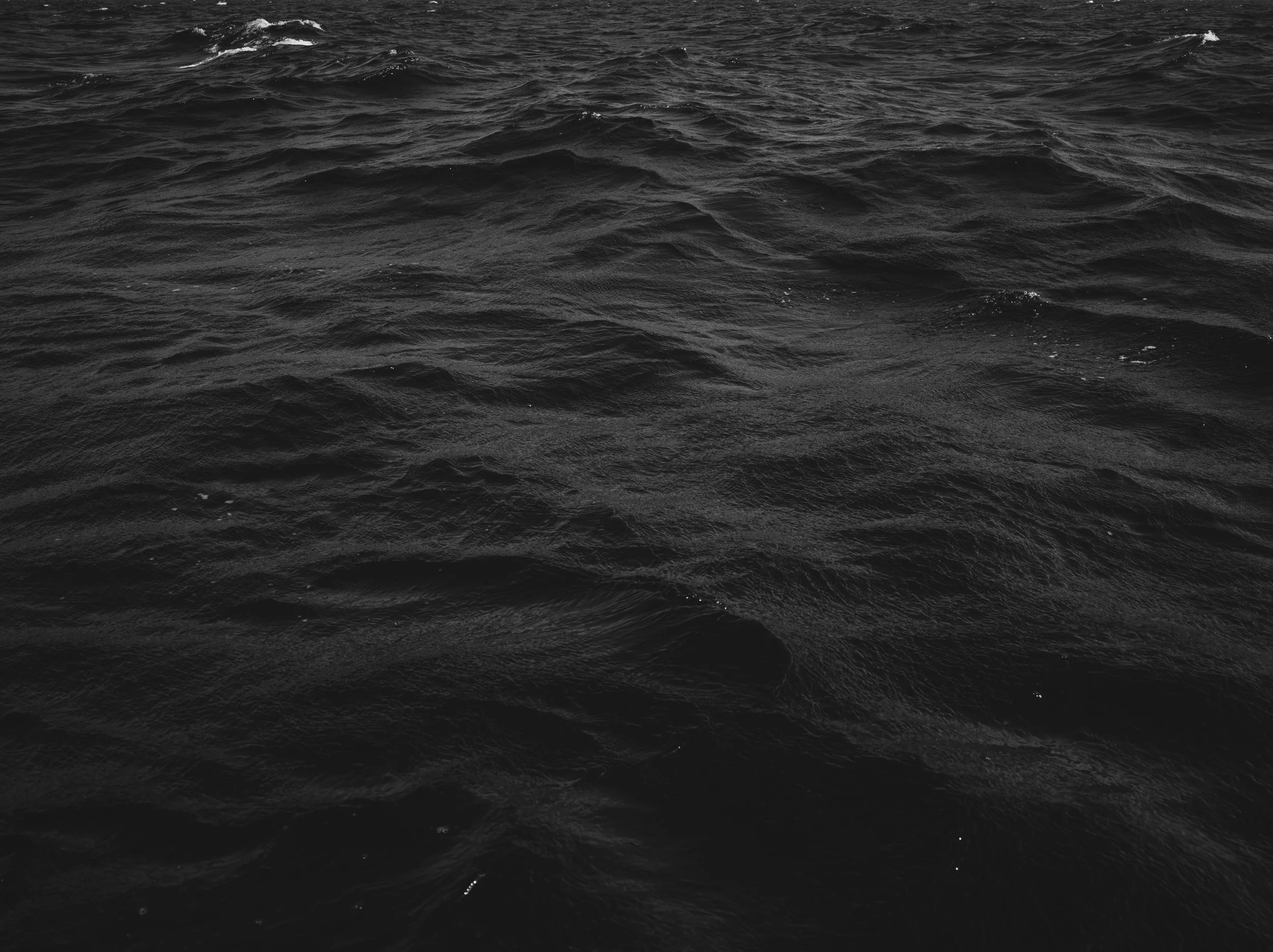 Black and white photograph of a choppy, wavy ocean surface.