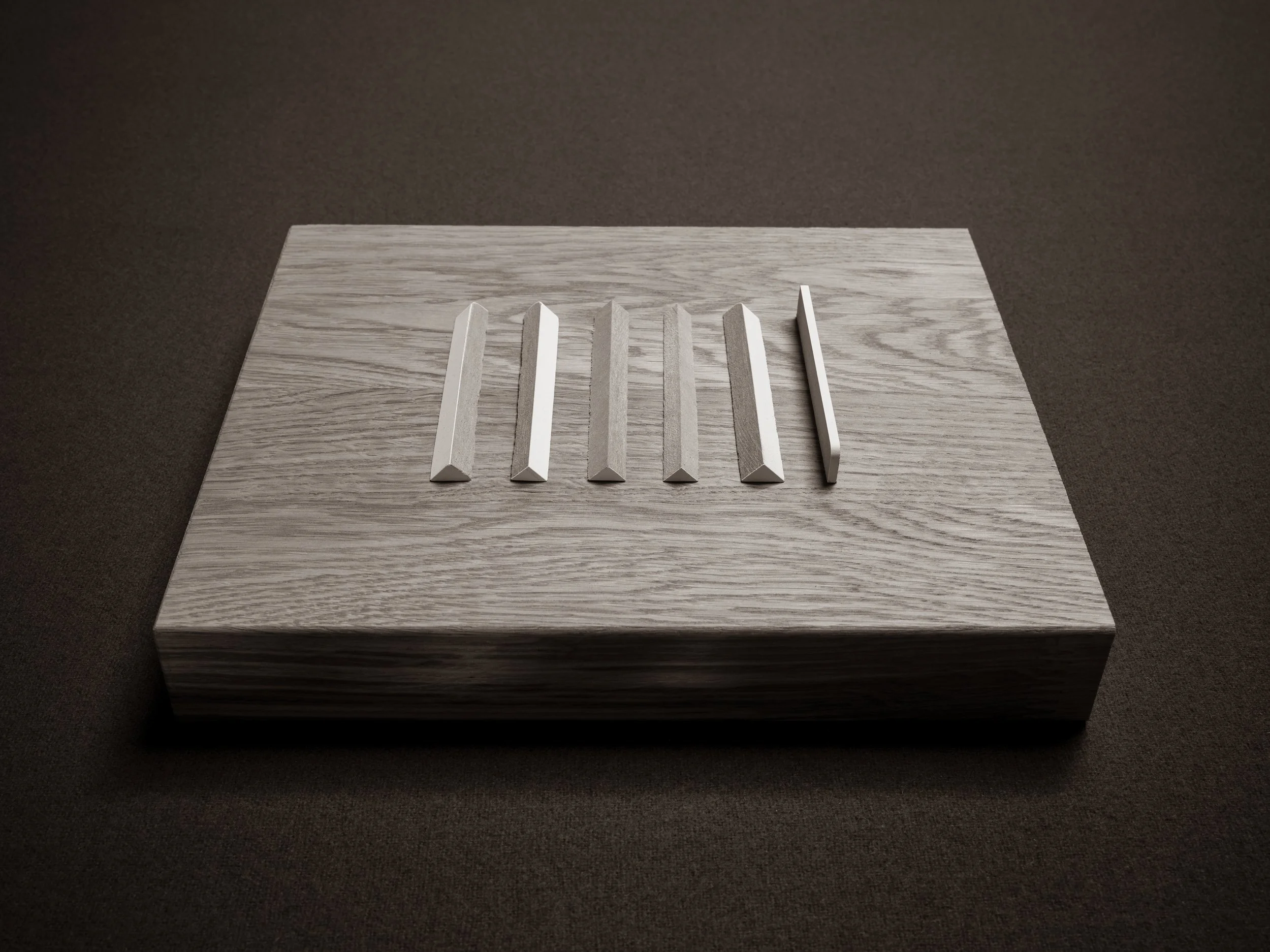 Several white rectangular and trapezoidal objects placed on a light gray wooden surface.