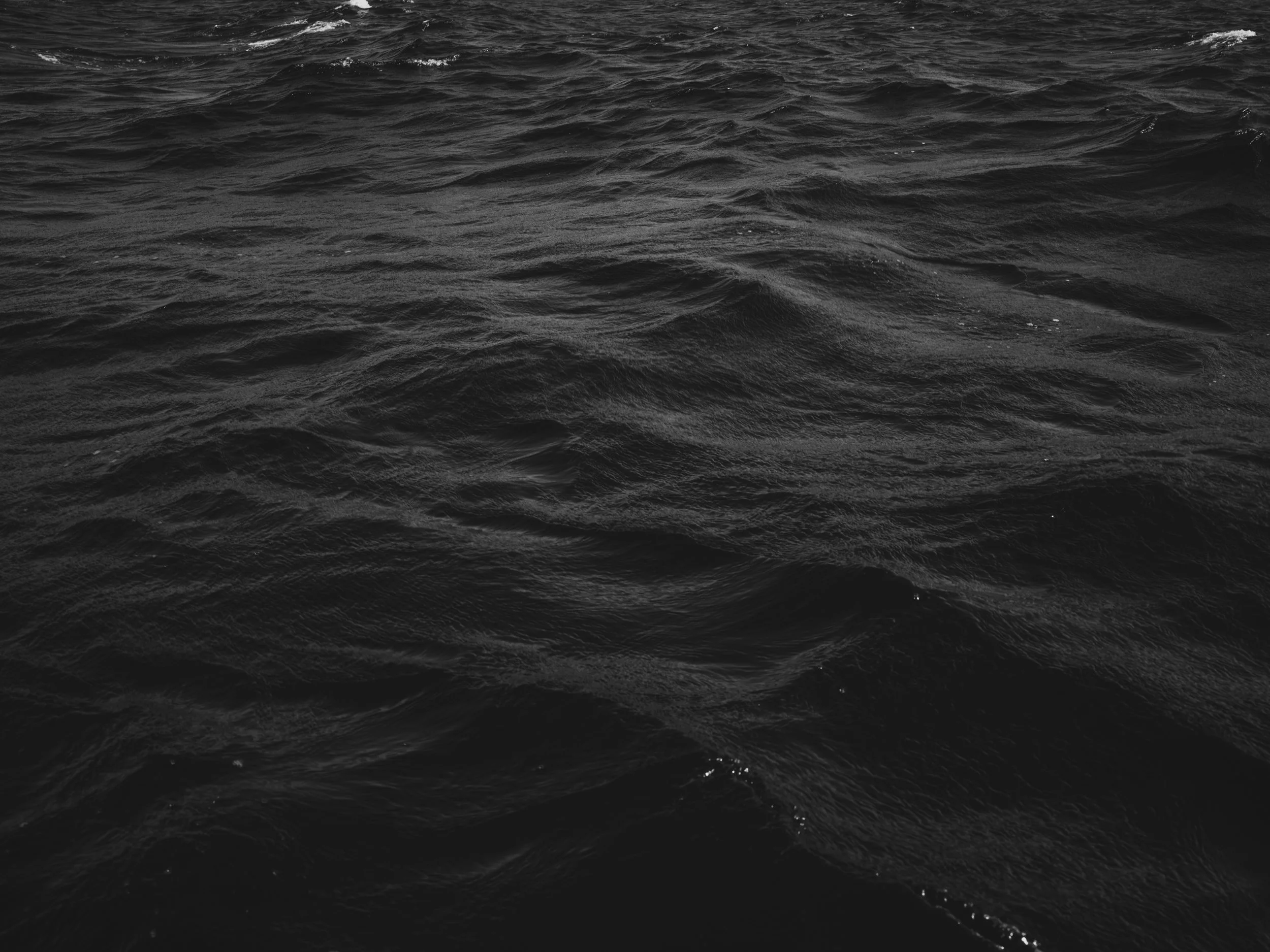 Black and white photo of ocean water with ripples and waves.