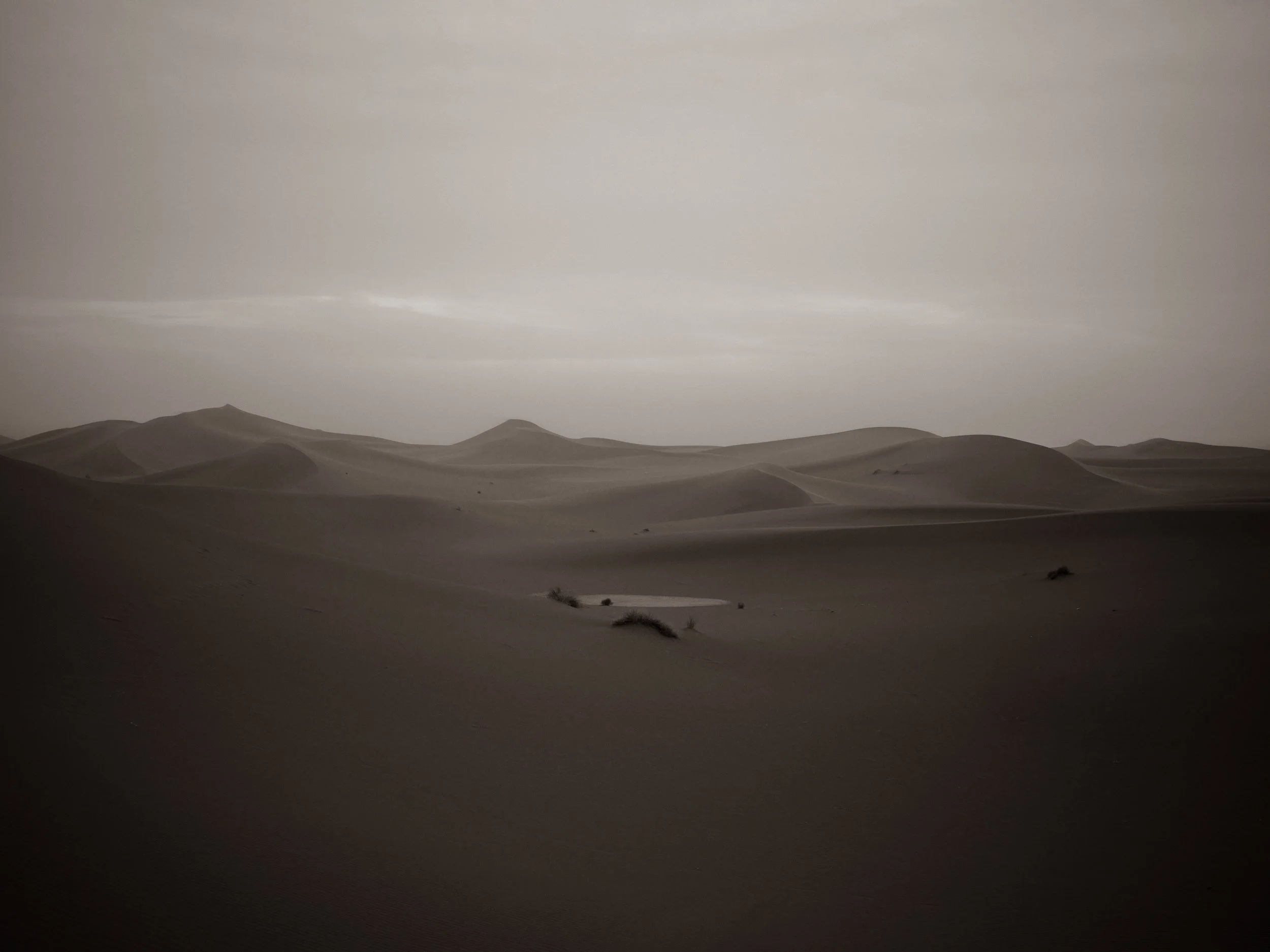 Desert landscape with rolling sand dunes under a cloudy sky
