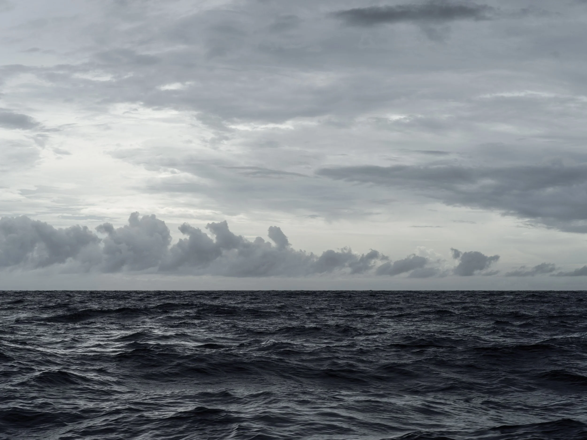 Cloudy sky over turbulent ocean water.