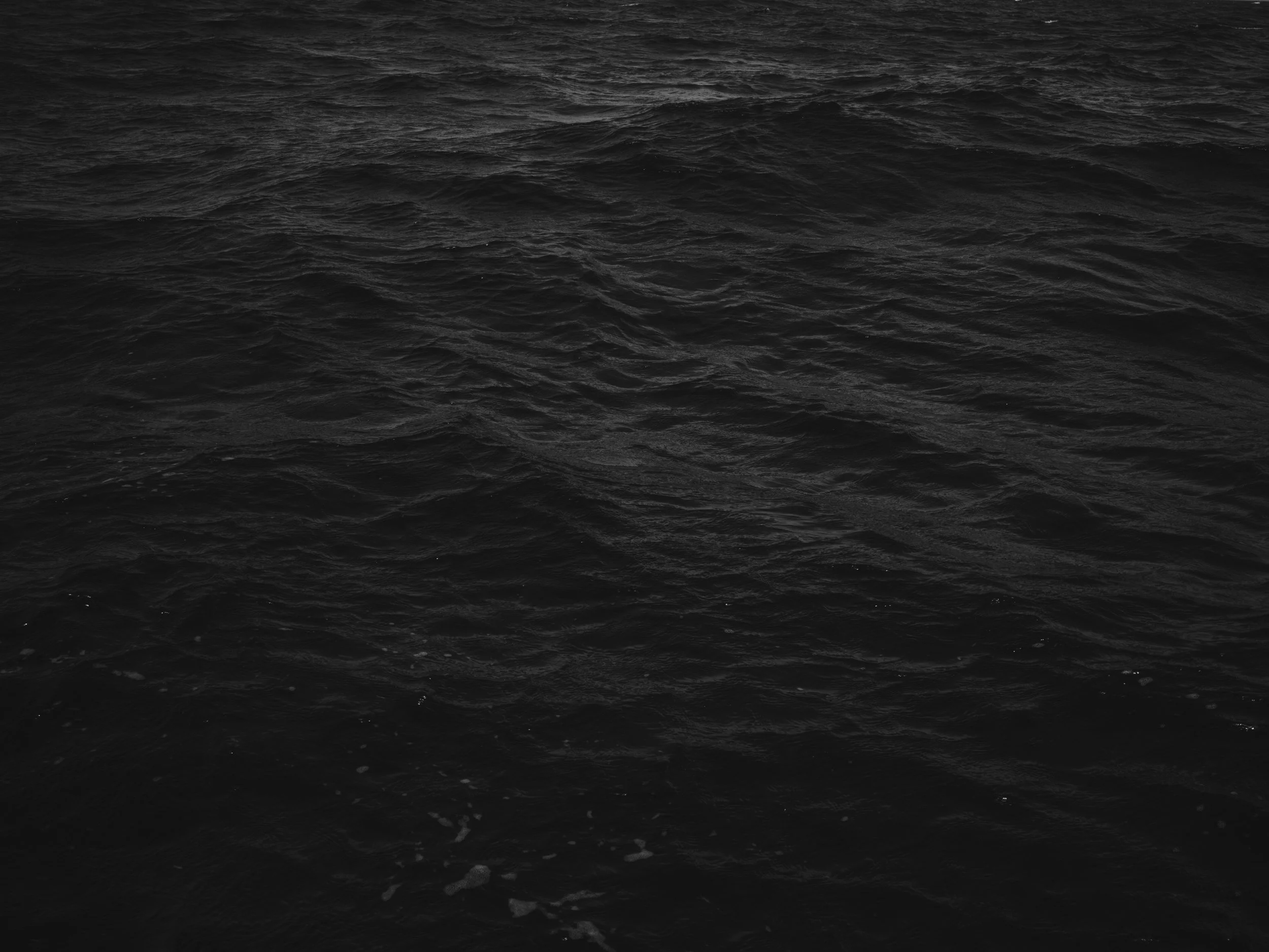 Dark ocean water with small waves and foam.