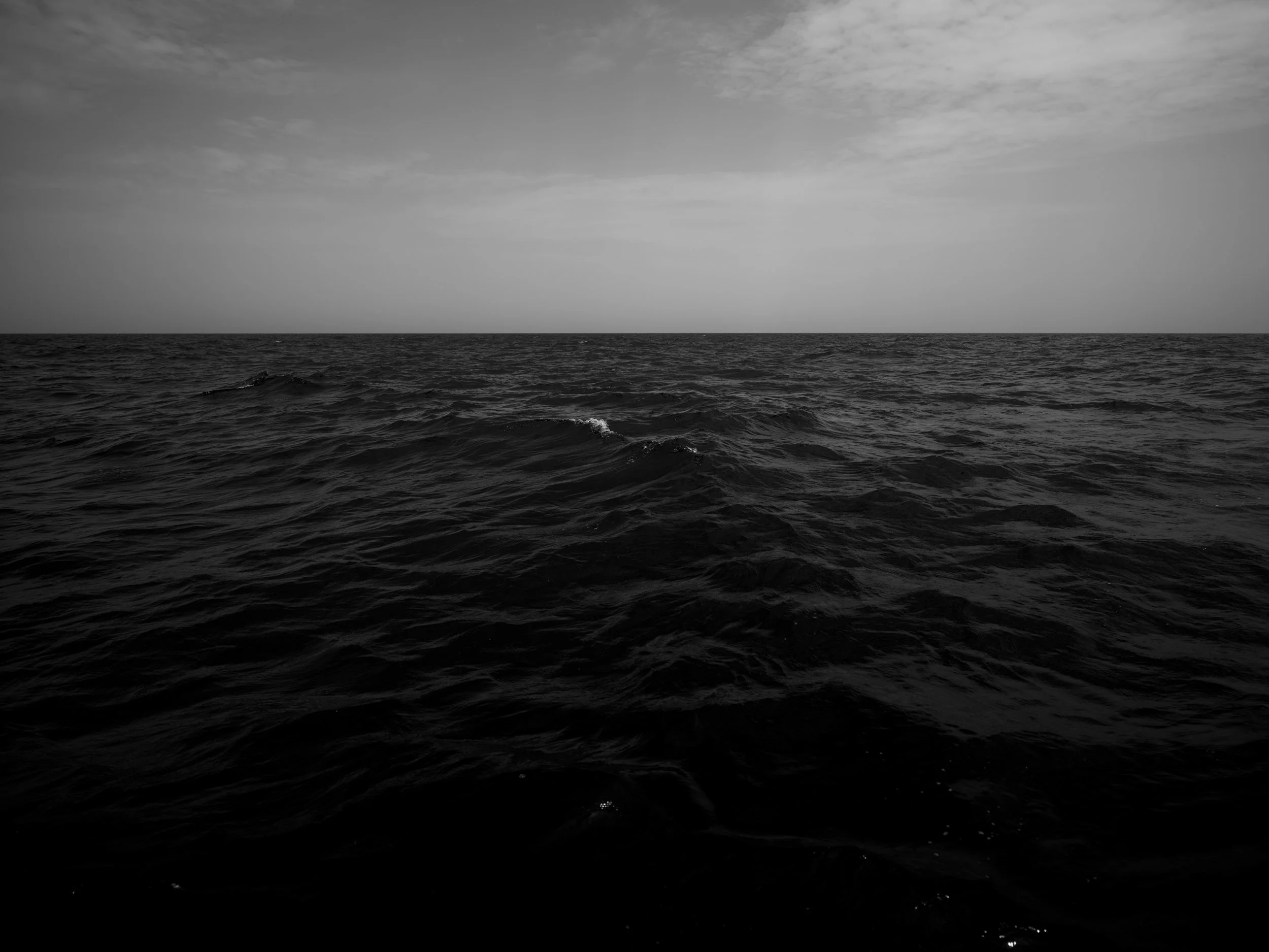 Vast ocean with small waves under a cloudy sky.