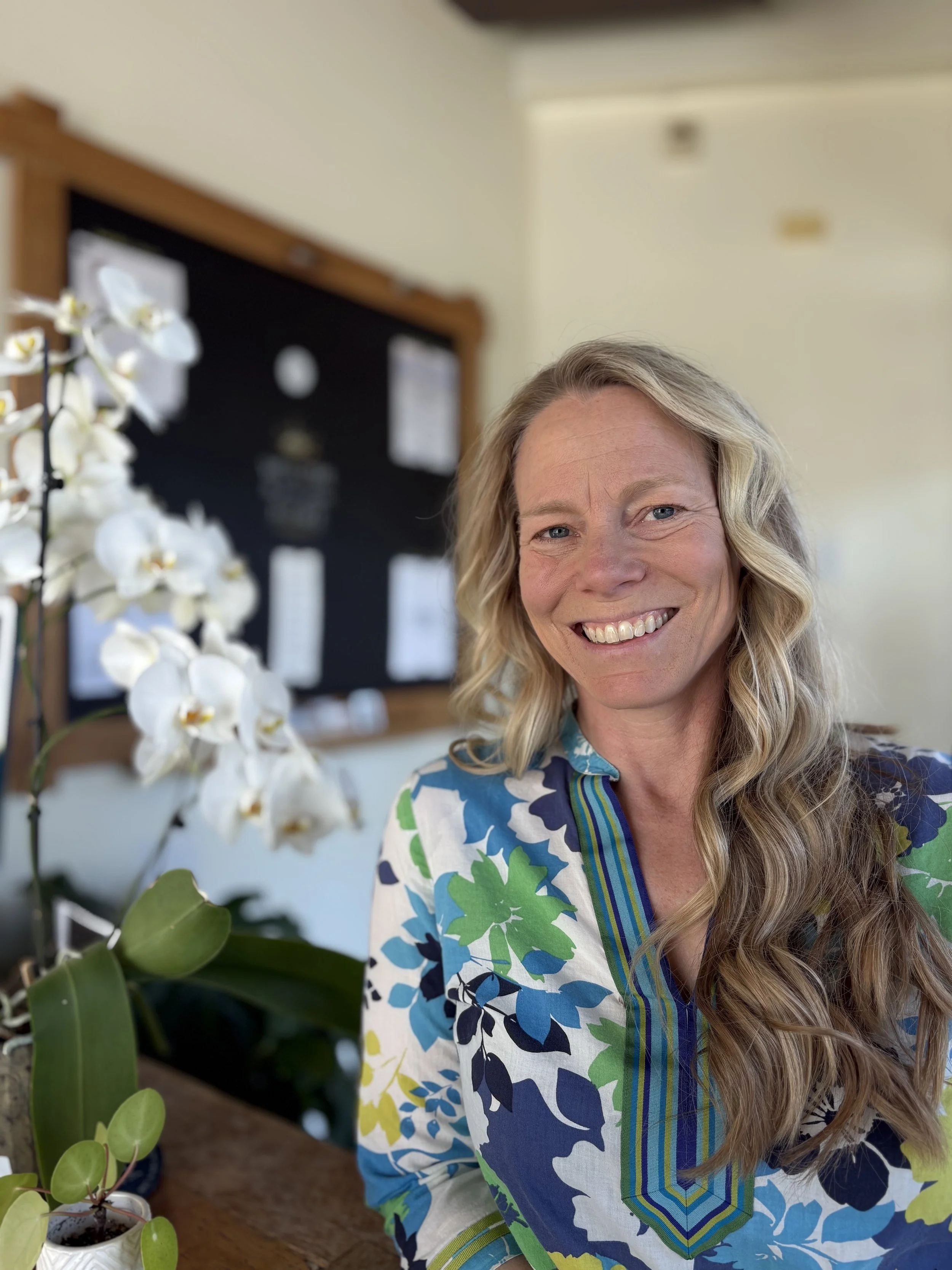 Polly Sackett LPC, SAC smiling near orchids