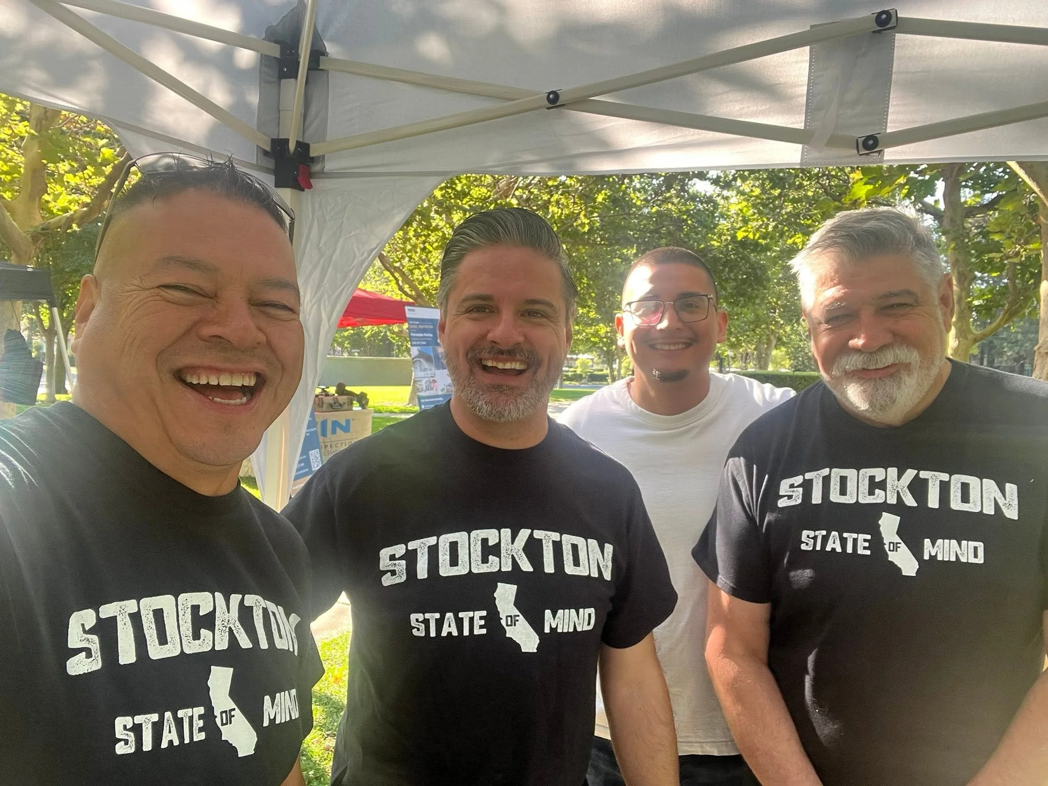 Group of people wearing black Stockton State of Mind graphic tees from Applaud Designs at an outdoor community event.