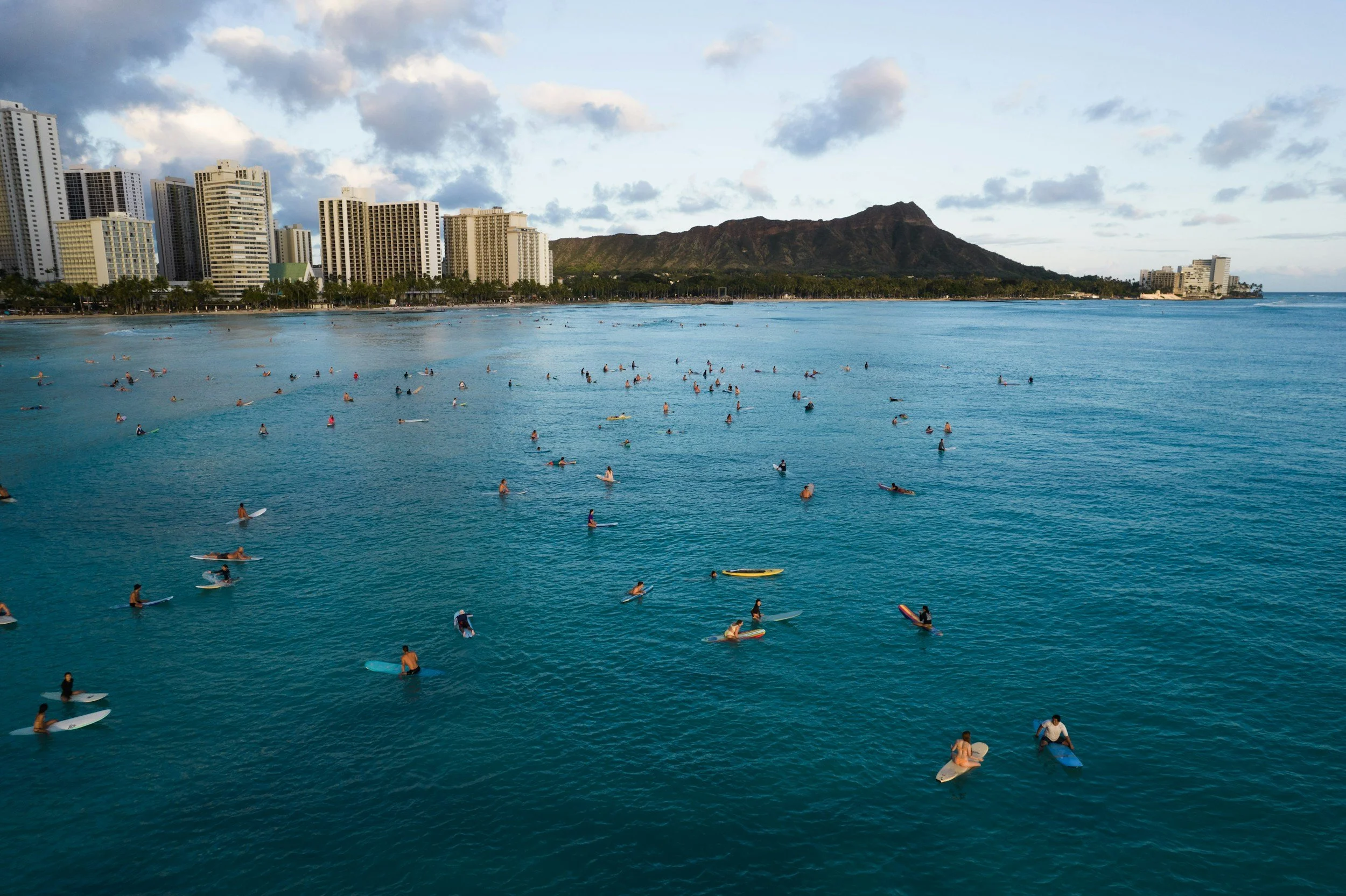 Surfers waiting in the lineup at Waikiki, Oahu, with Diamond Head and the Waikiki skyline behind