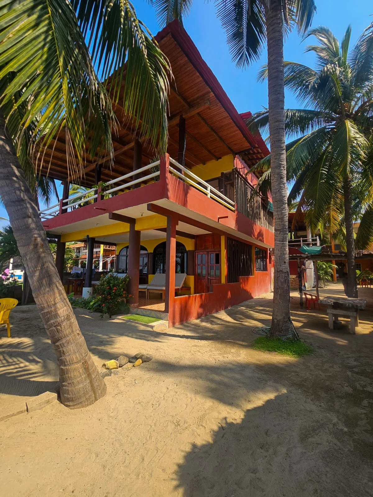 Casa Esmeralda's balconies framed by palm trees on the beach