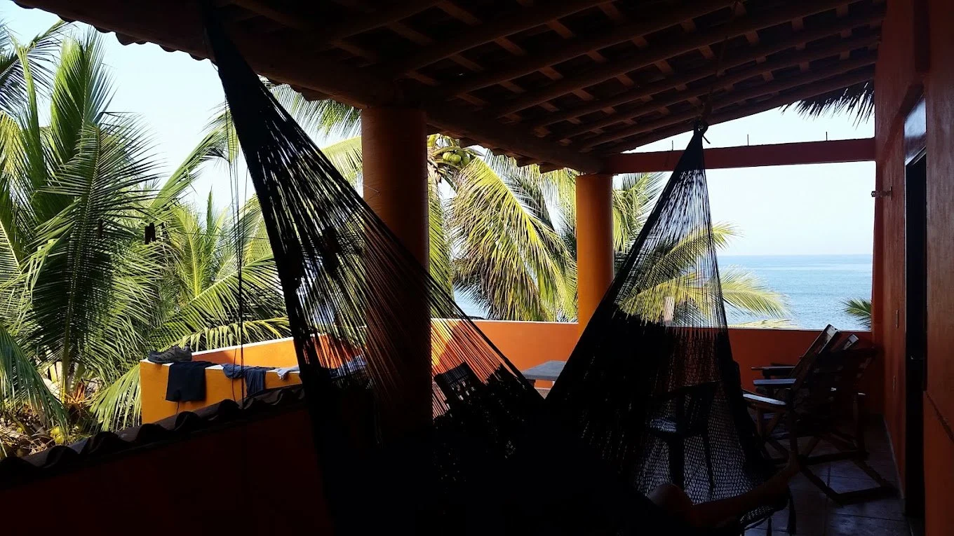 Hammock on a shaded terrace at Casa Esmeralda with palm trees and an ocean view
