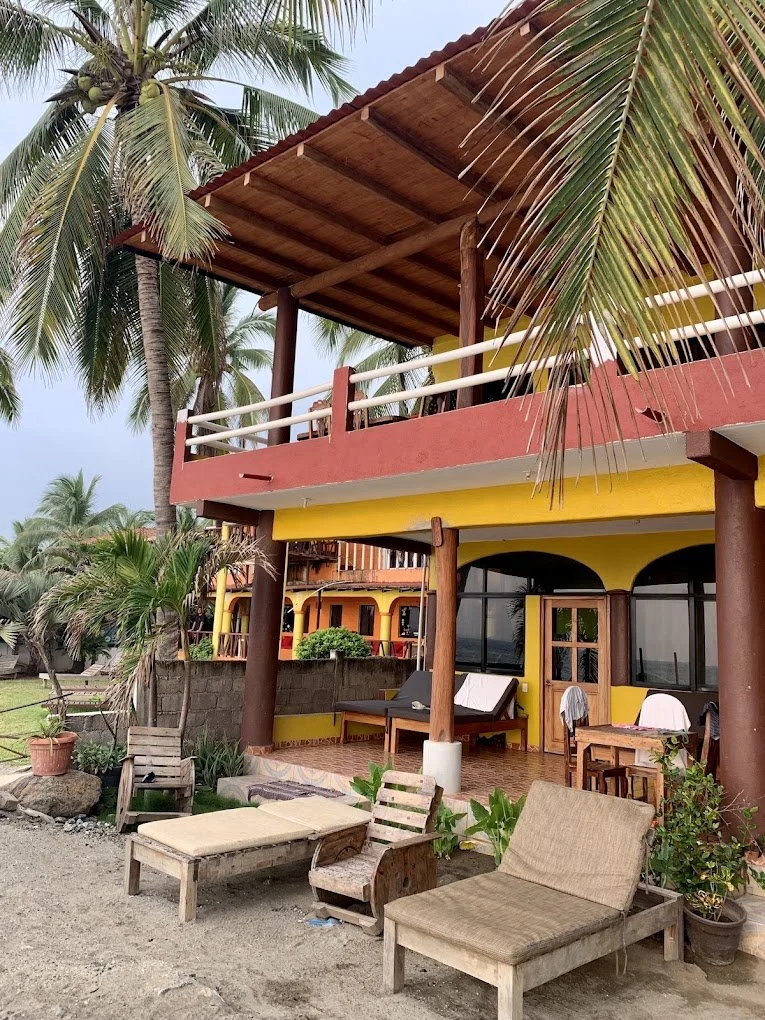 Beachfront patio with wooden loungers in front of the three-story house