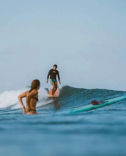 Two surfers riding a wave at La Saladita, Mexico