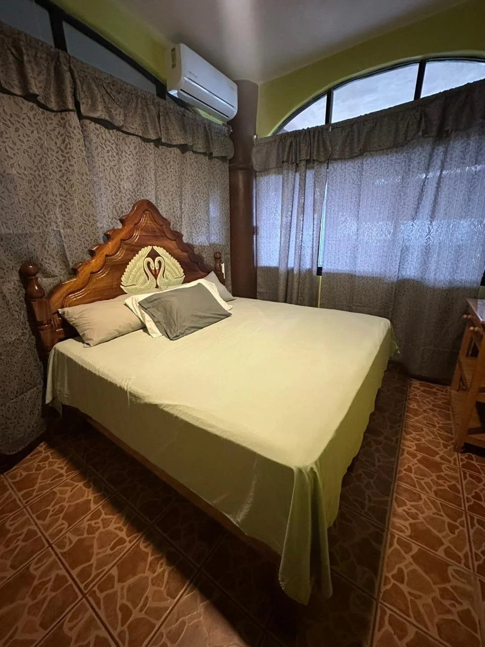 Bedroom with a double bed, carved wooden headboard and arched window