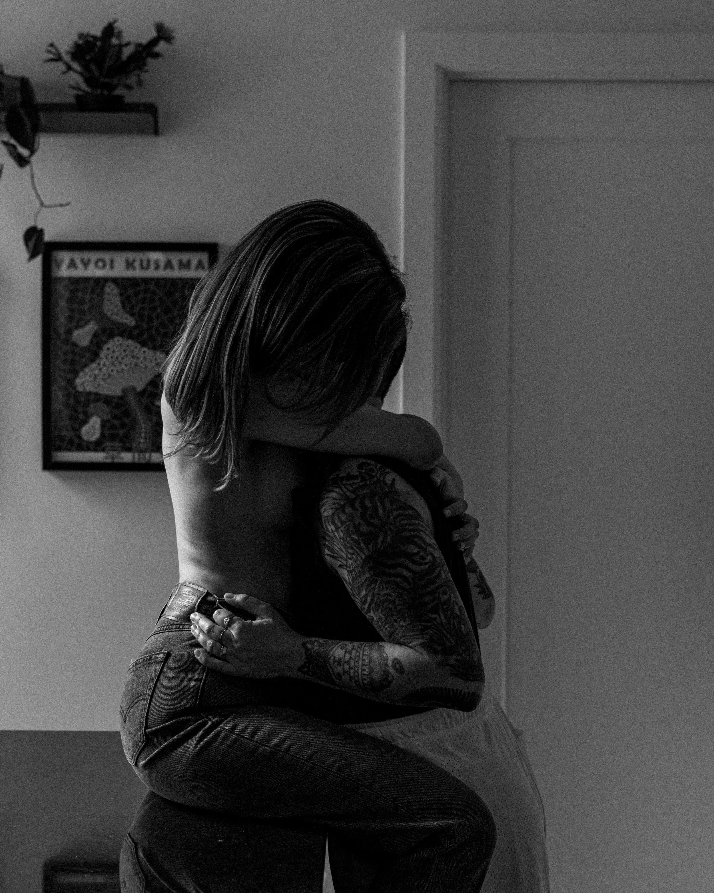 Un couple s'embrasse dans un intérieur, la femme a des tatouages sur le bras.