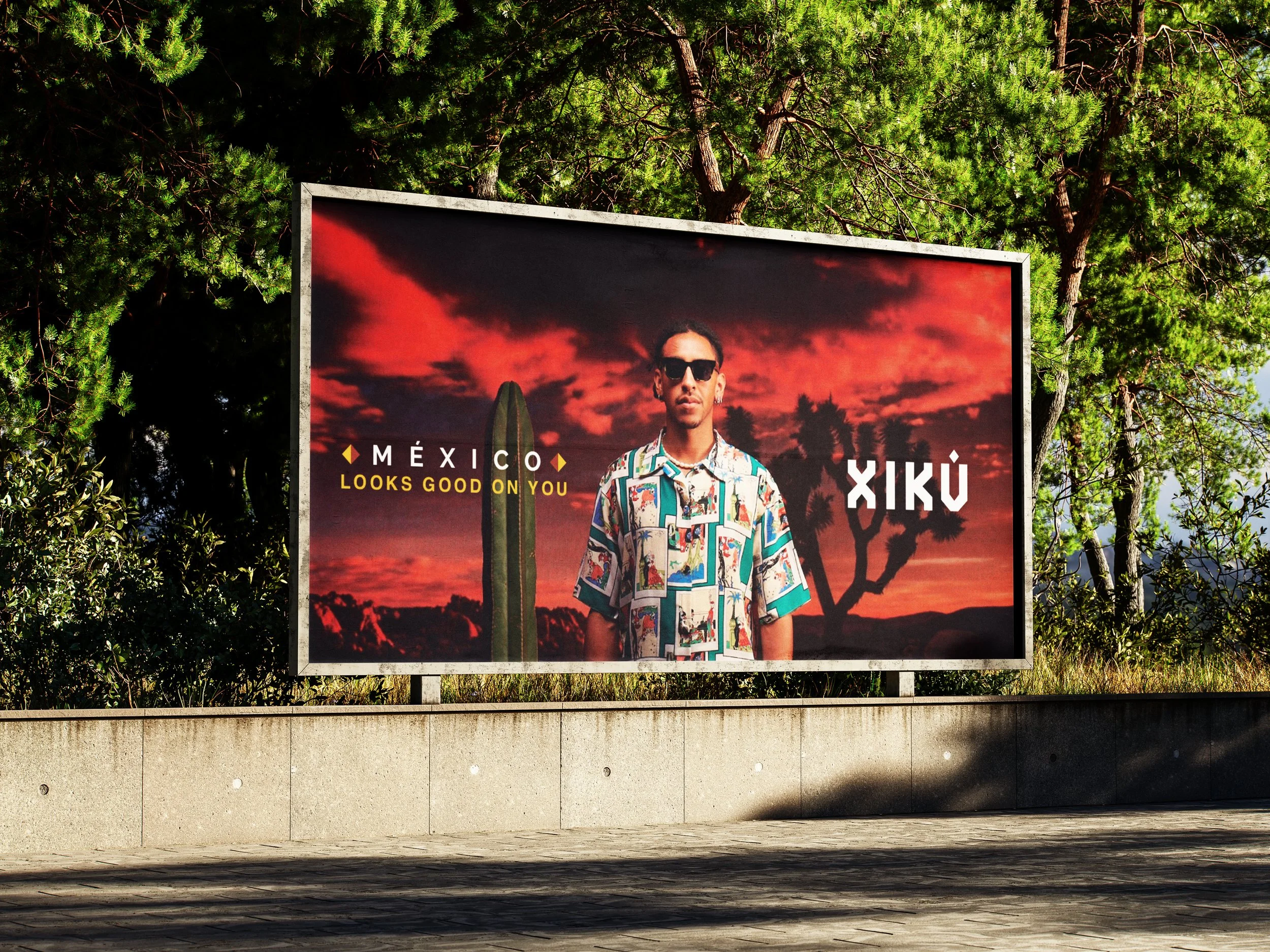 Cartel publicitario con una persona usando lentes oscuros y peinado moderno, con un fondo de atardecer rojo y árboles de fondo, en la ciudad de México.