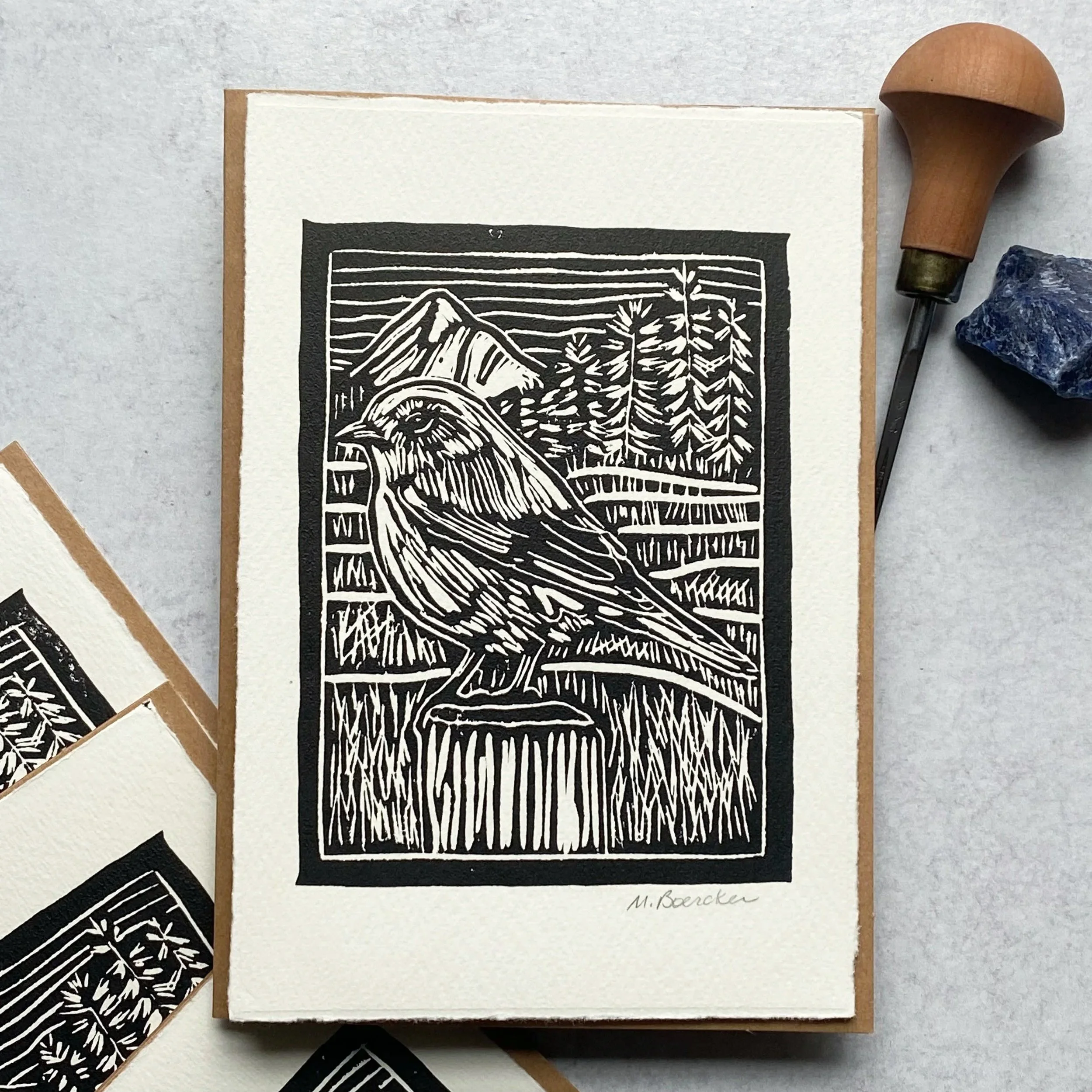 A black and white line drawing of a mountain landscape with trees and a signature at the bottom right.