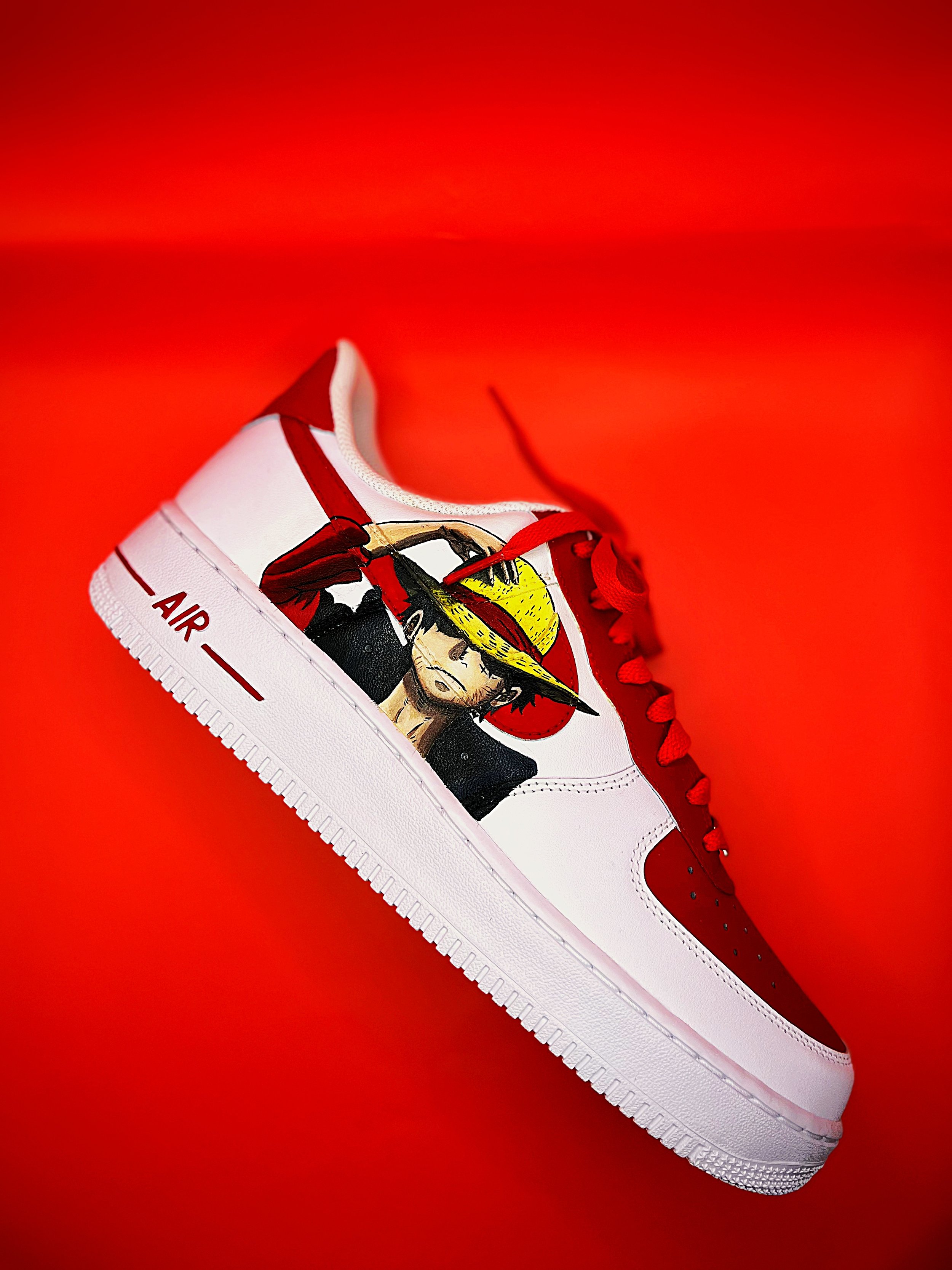 White sneaker with red accents and a graphic of a woman wearing a yellow hat on the side, set against a red background.