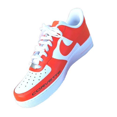 A white and orange Nike sneaker with the word 'CORVETTE' written on the side, on a black background.