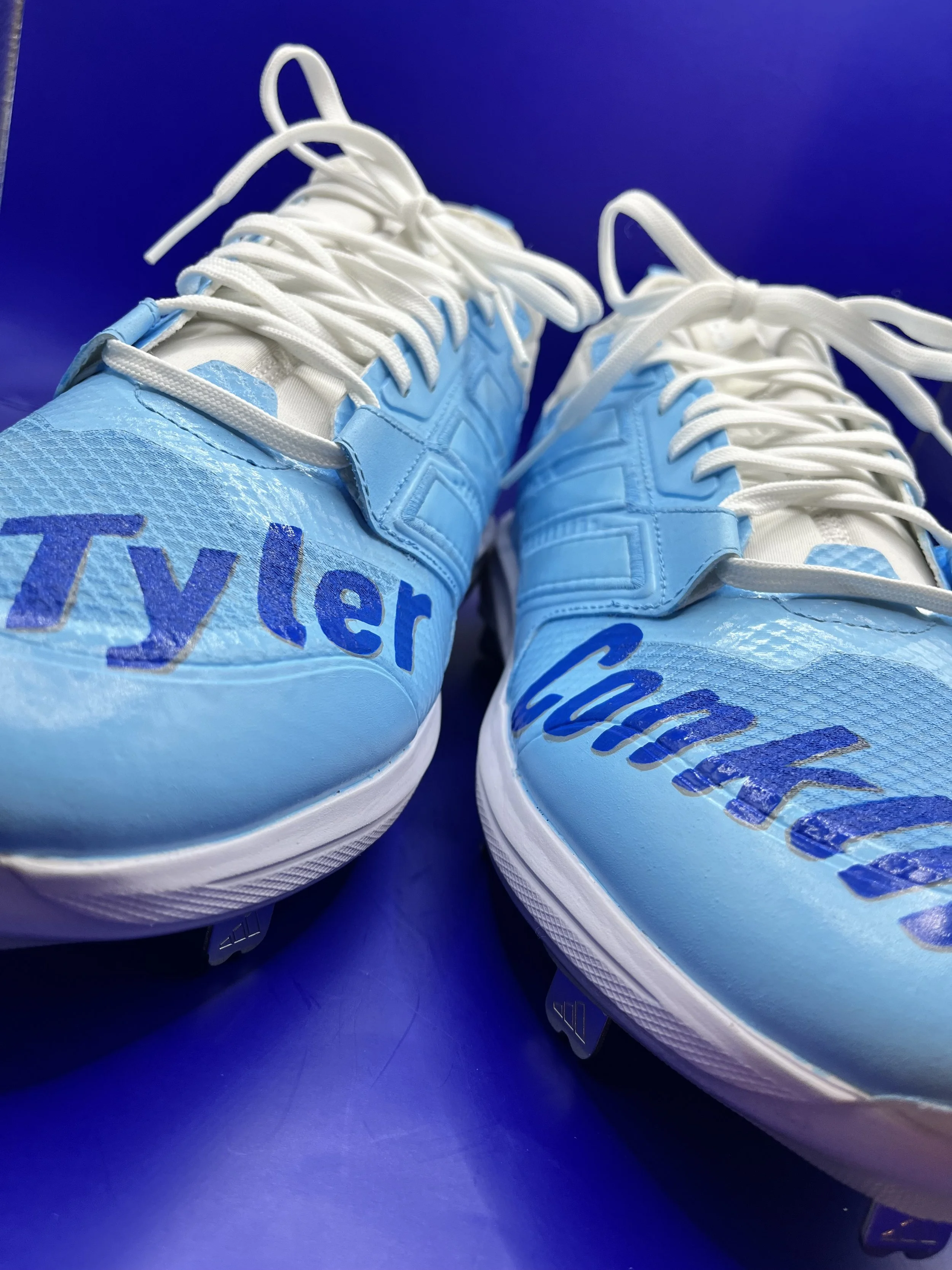 Close-up of light blue sneakers with white laces on a blue surface.