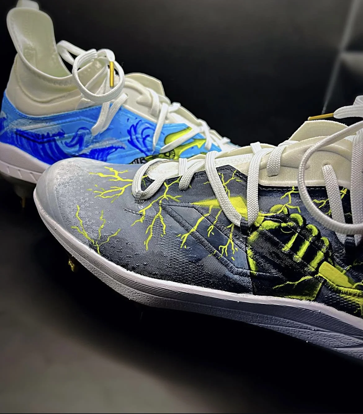 Colorful athletic shoes with lightning bolt and storm graphic designs, placed on a black surface.