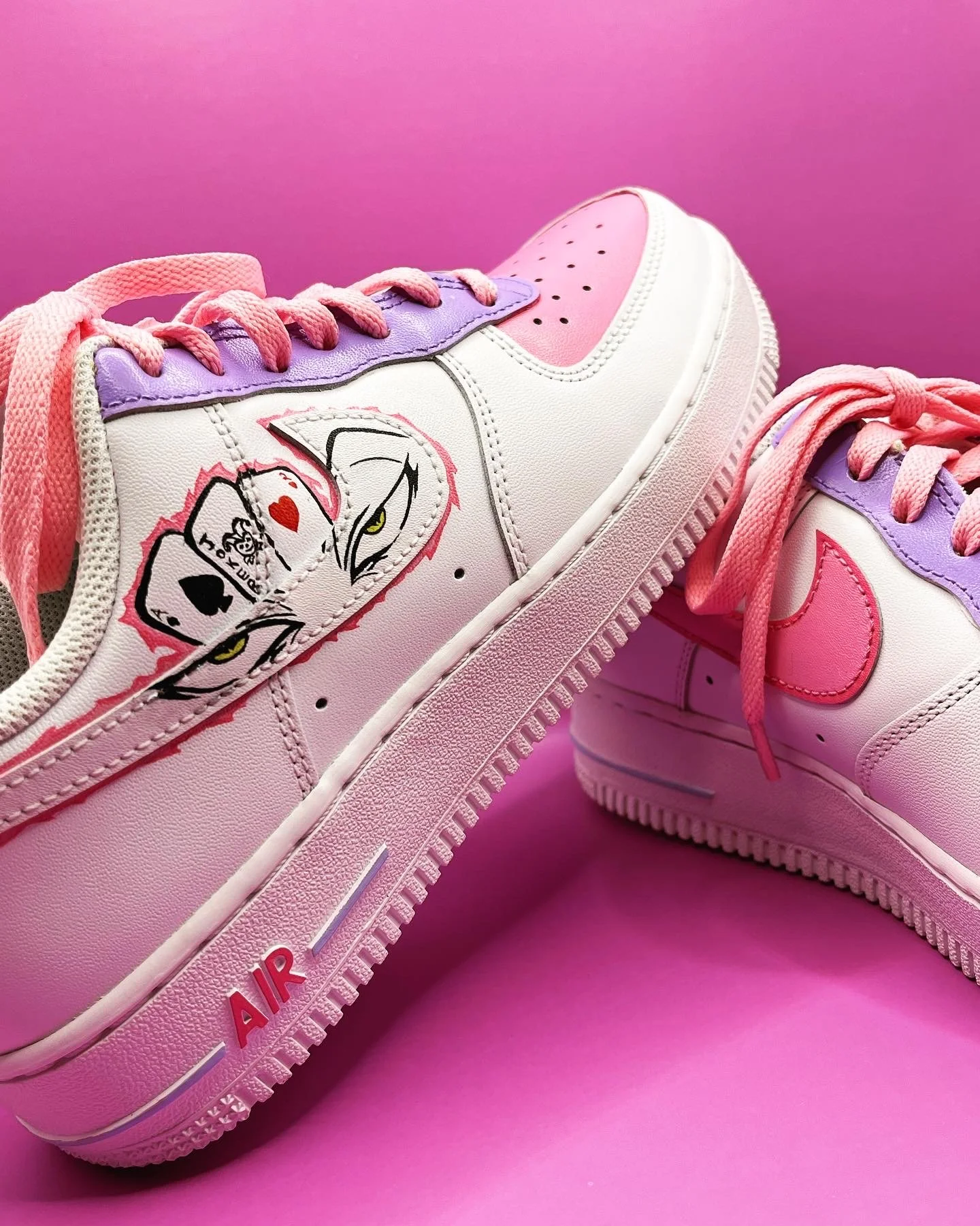 Close-up of stylish sneakers with pink, purple, and white color details against a pink background.
