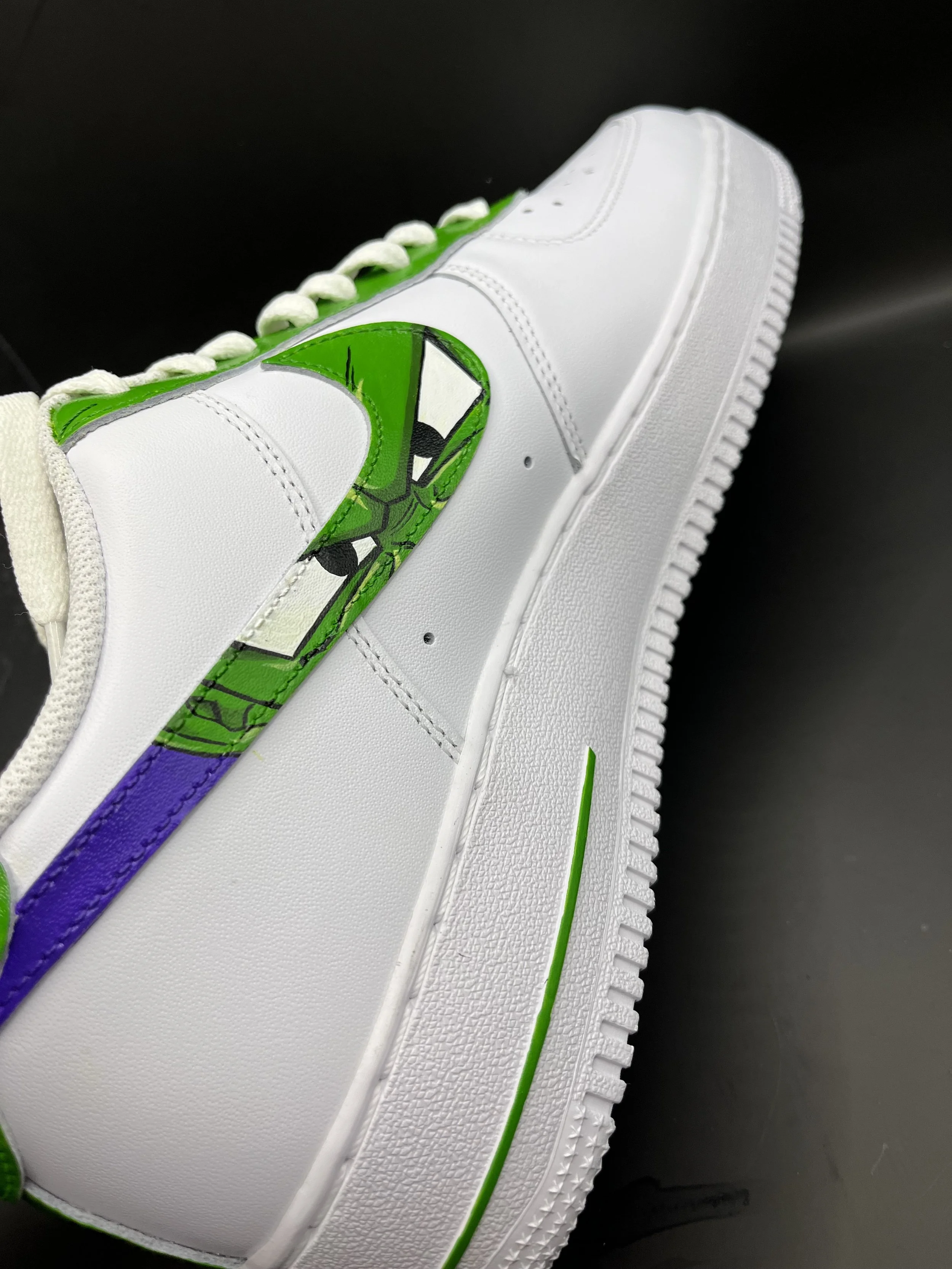 Close-up of a white sneaker with a colorful graphic of a turtle and a rainbow on the side, set against a black background.